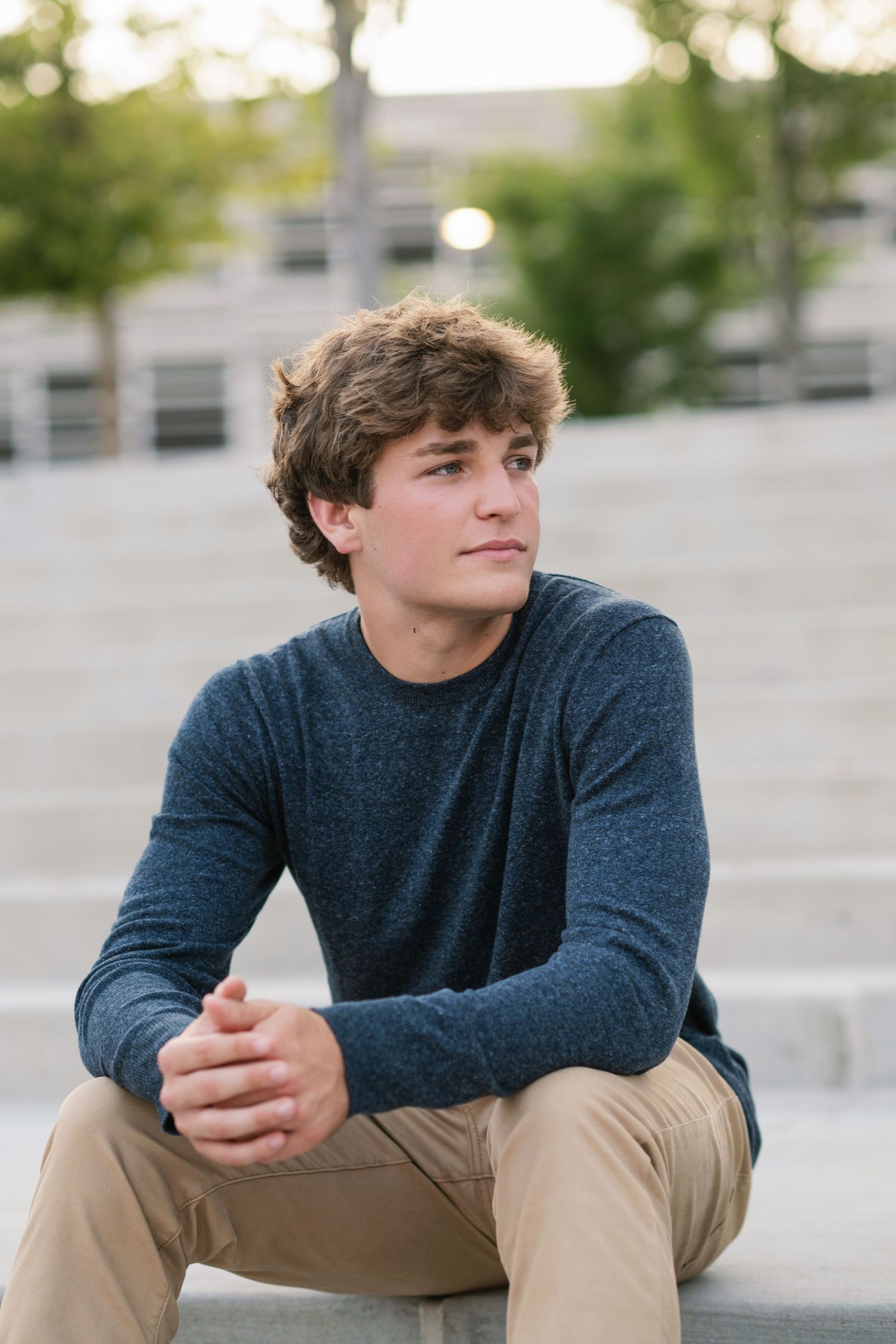 Person in navy sweater sits contemplatively on outdoor steps.