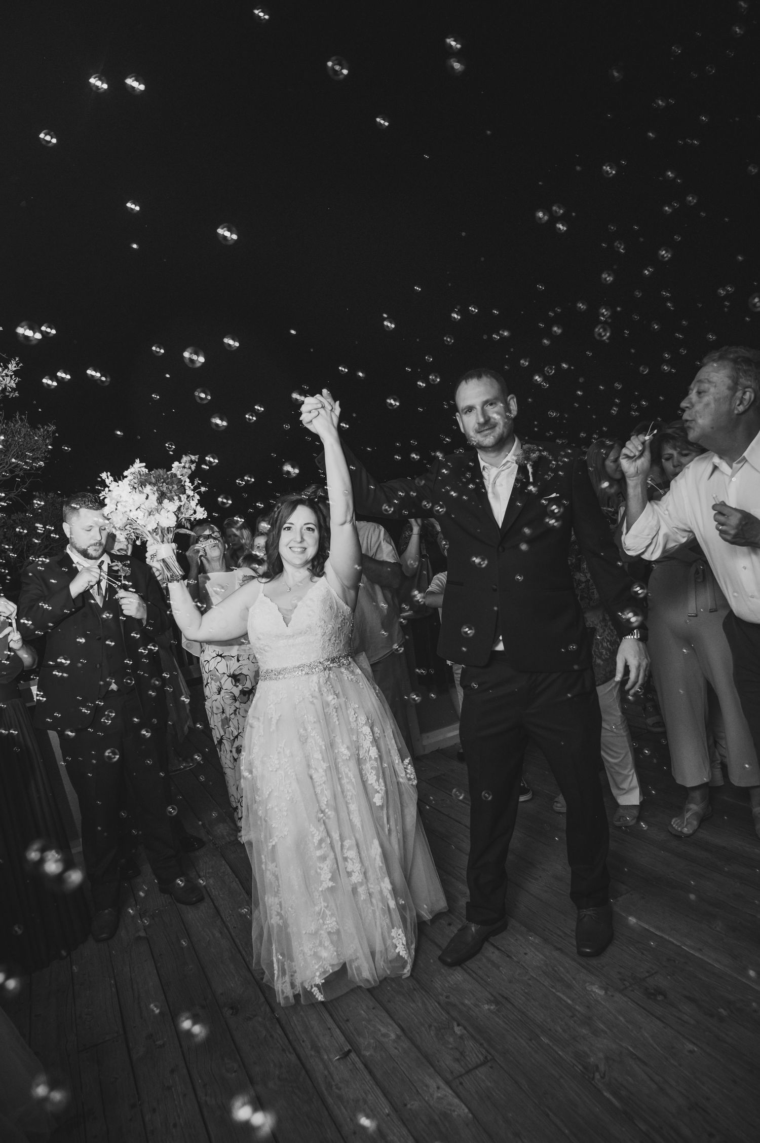 Black and white image of wedding celebration with confetti falling on dance floor.