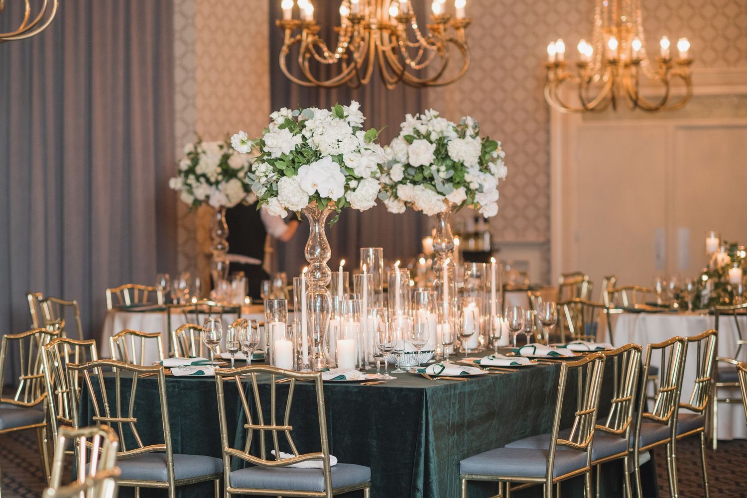 Luxurious wedding reception hall with crystal chandeliers and formal table settings.