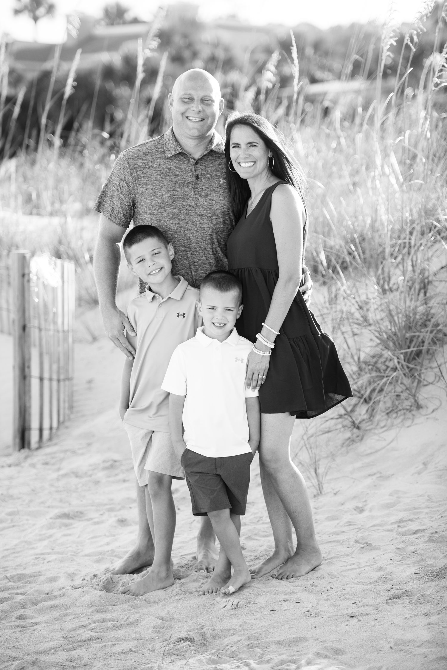 Black and white beach portraits showing playful family moments on sandy dunes with beach grass. Hammock Beach