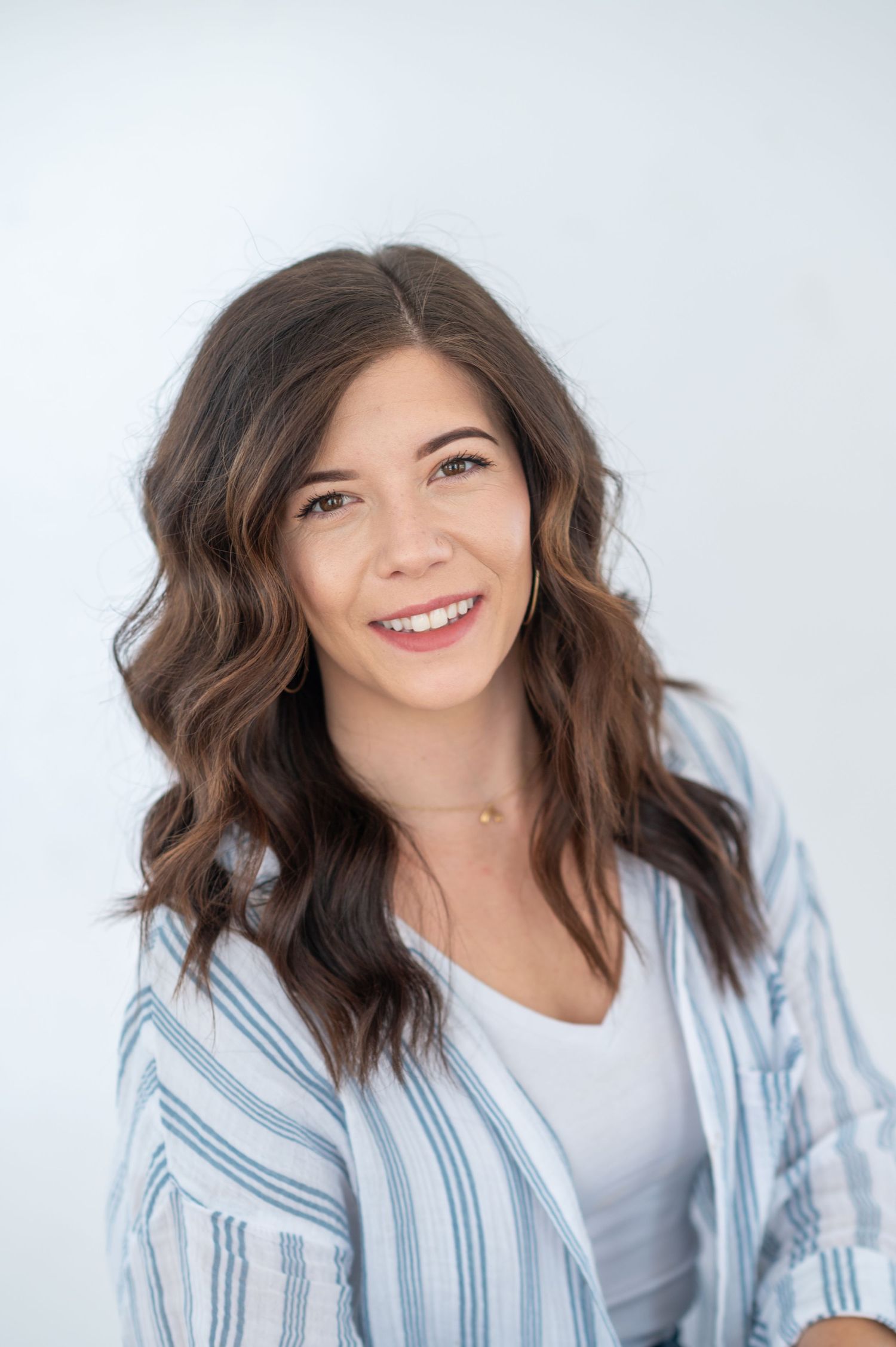 Lifestyle portraits featuring wavy hair and blue striped shirt against light background.