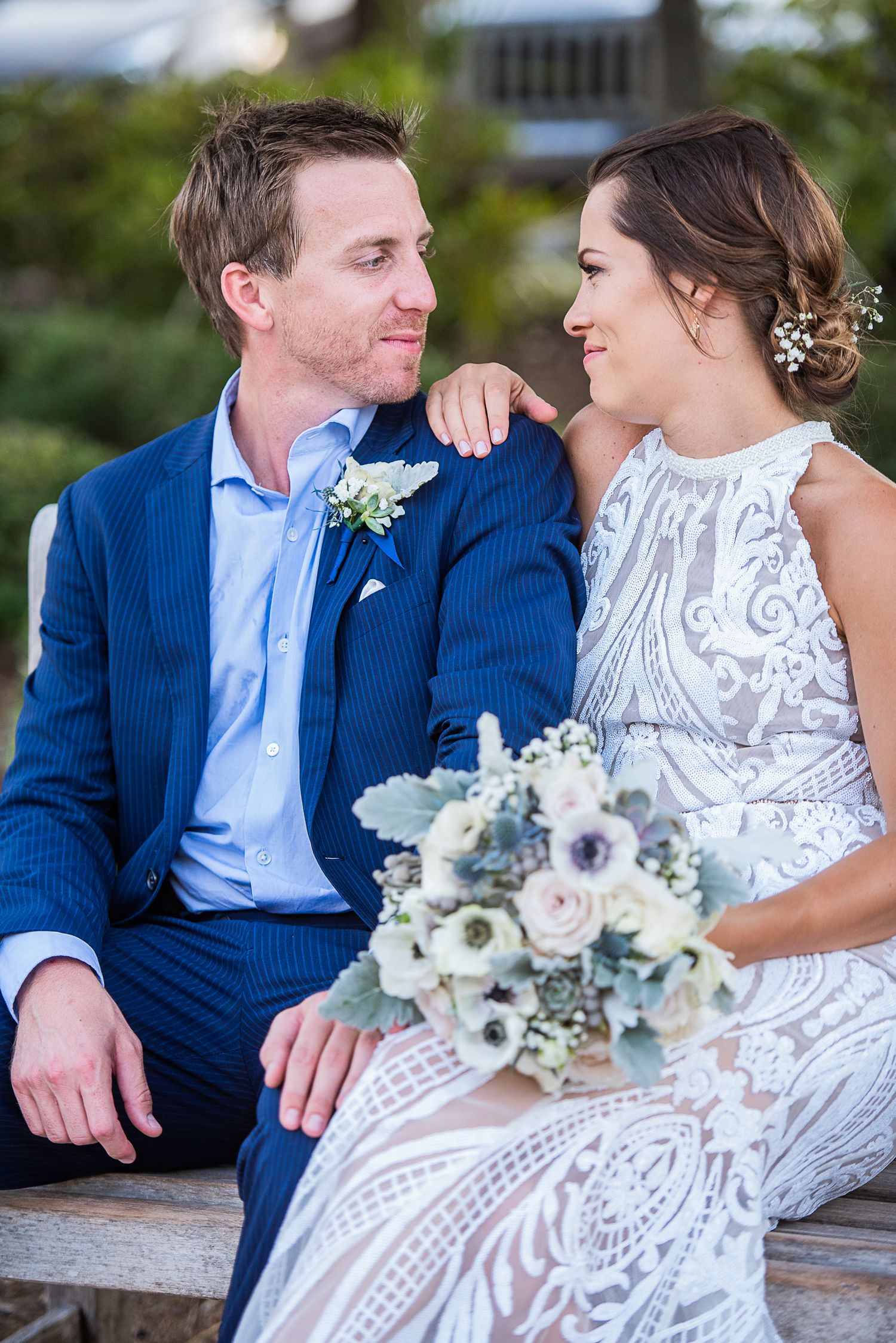 Wedding couple in white dress and blue suit sitting together with floral bouquet. Hilton Head Wedding.