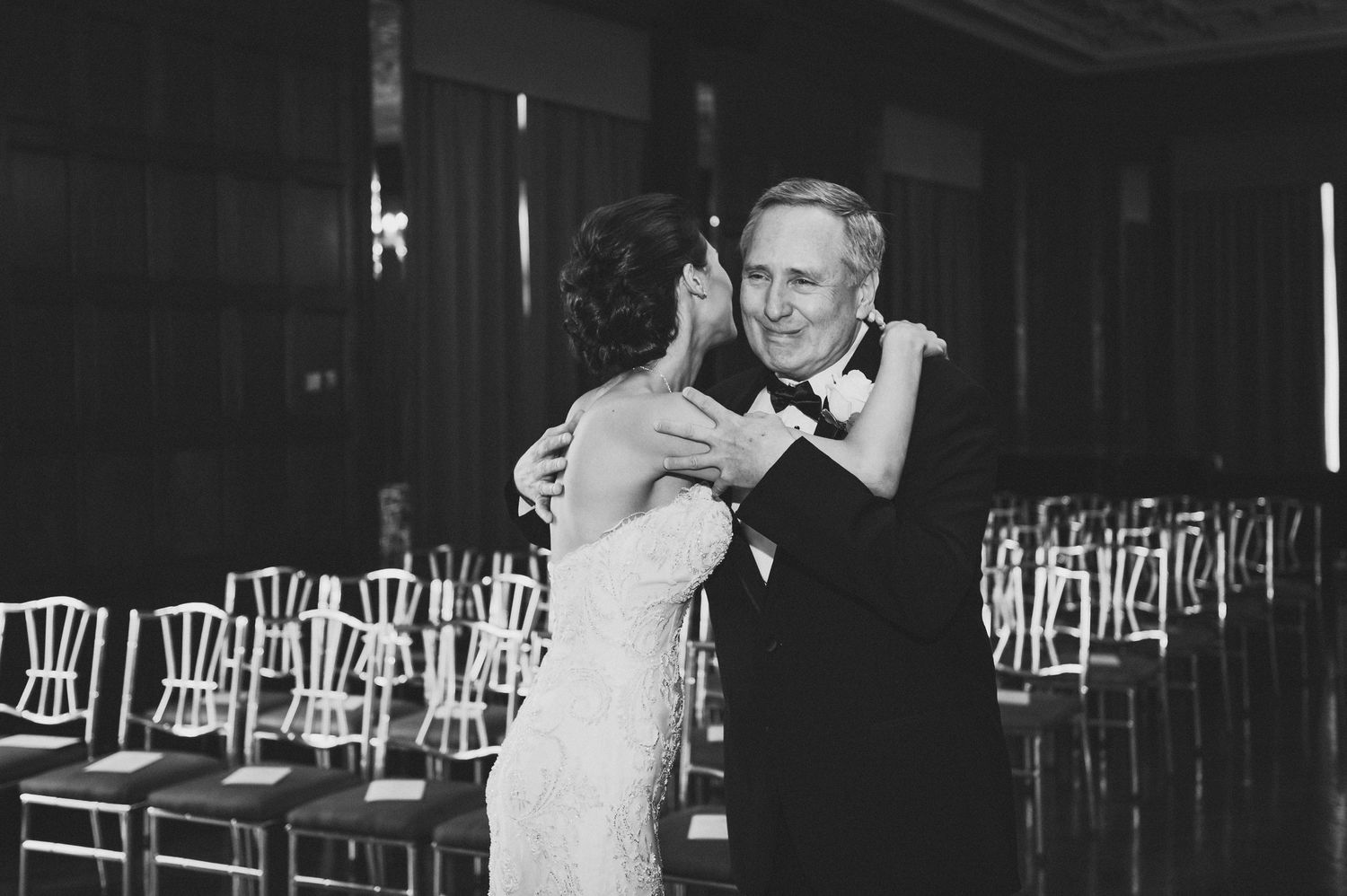 A couple dances together at what appears to be their wedding reception in a black and white photograph.