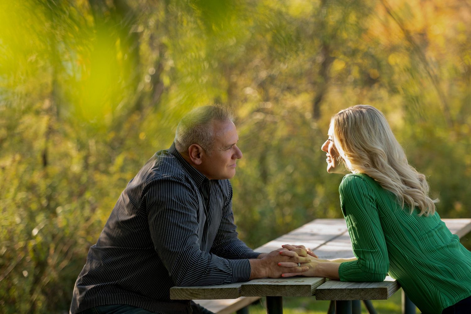 Series of candid romantic moments between couple on wooden bench in park setting.