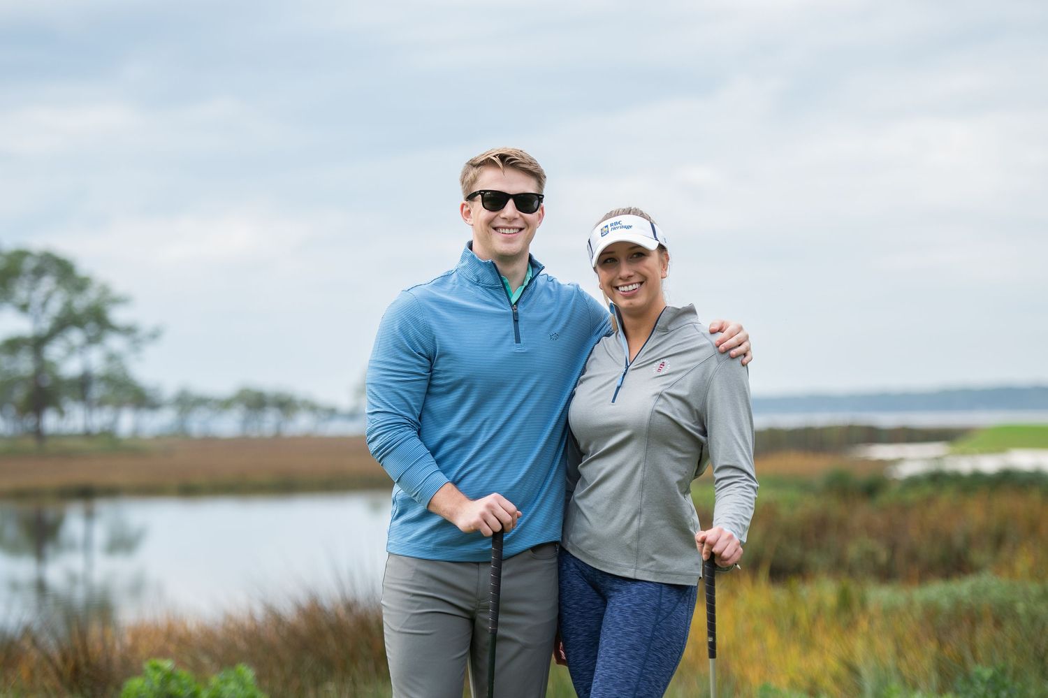 Golfers sharing a friendly moment on coastal golf course during sunny day.