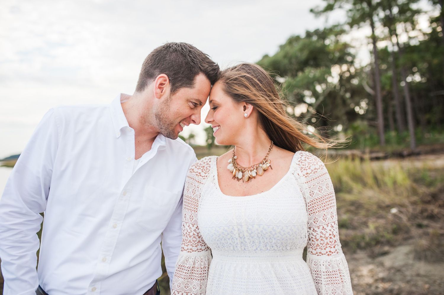 Romantic couple in white outfits embracing on a beach during sunset photoshoot. Palmetto Bluff