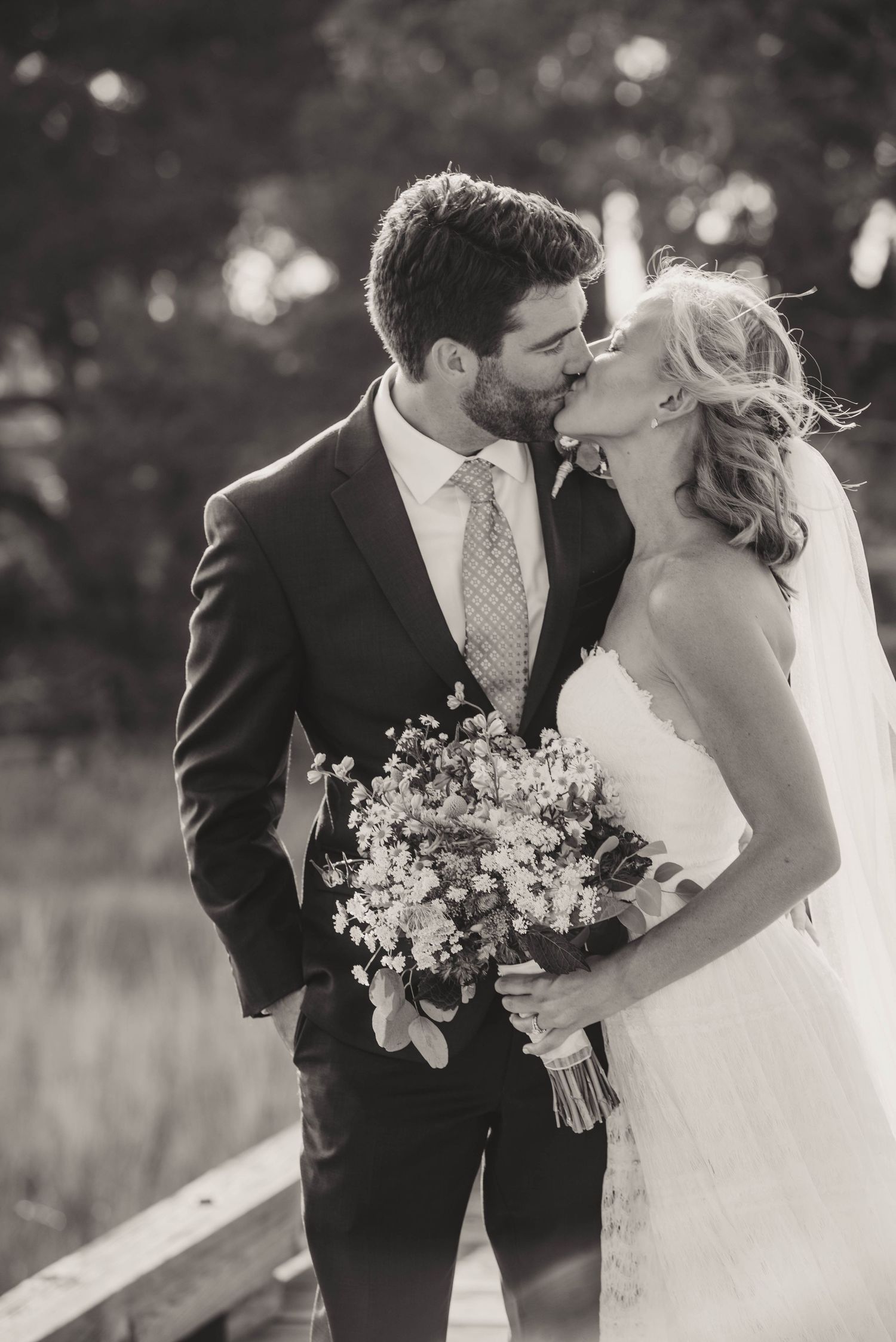 Black and white wedding portraits of a couple sharing intimate moments with bouquet in an outdoor marsh coastal setting.