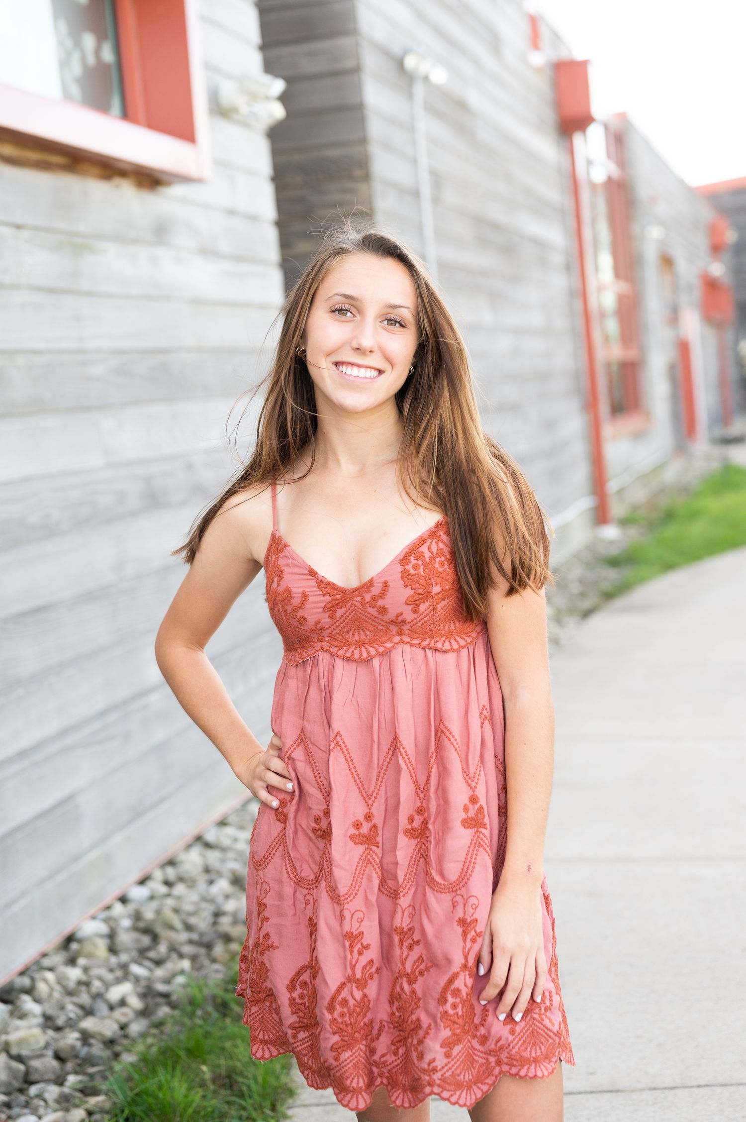 A person in a coral-colored lace top poses outdoors against a concrete wall in a series of casual portraits.