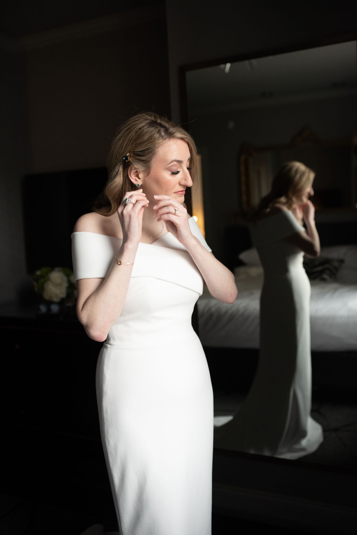 Artistic sequence of a bride in white getting ready in a dimly lit room with mirror reflections.