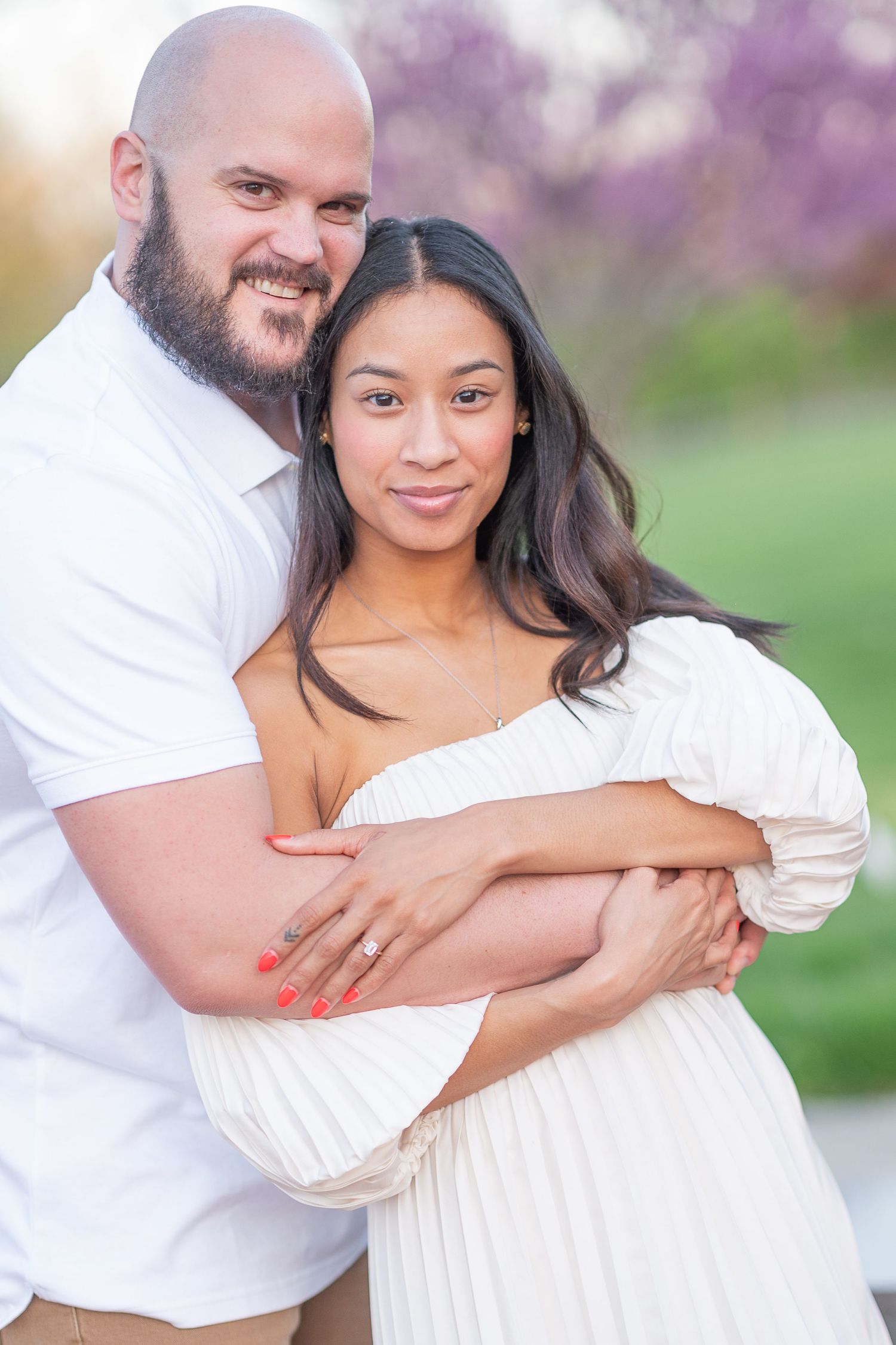 Spring engagement photos with blooming purple trees in soft dreamy lighting.