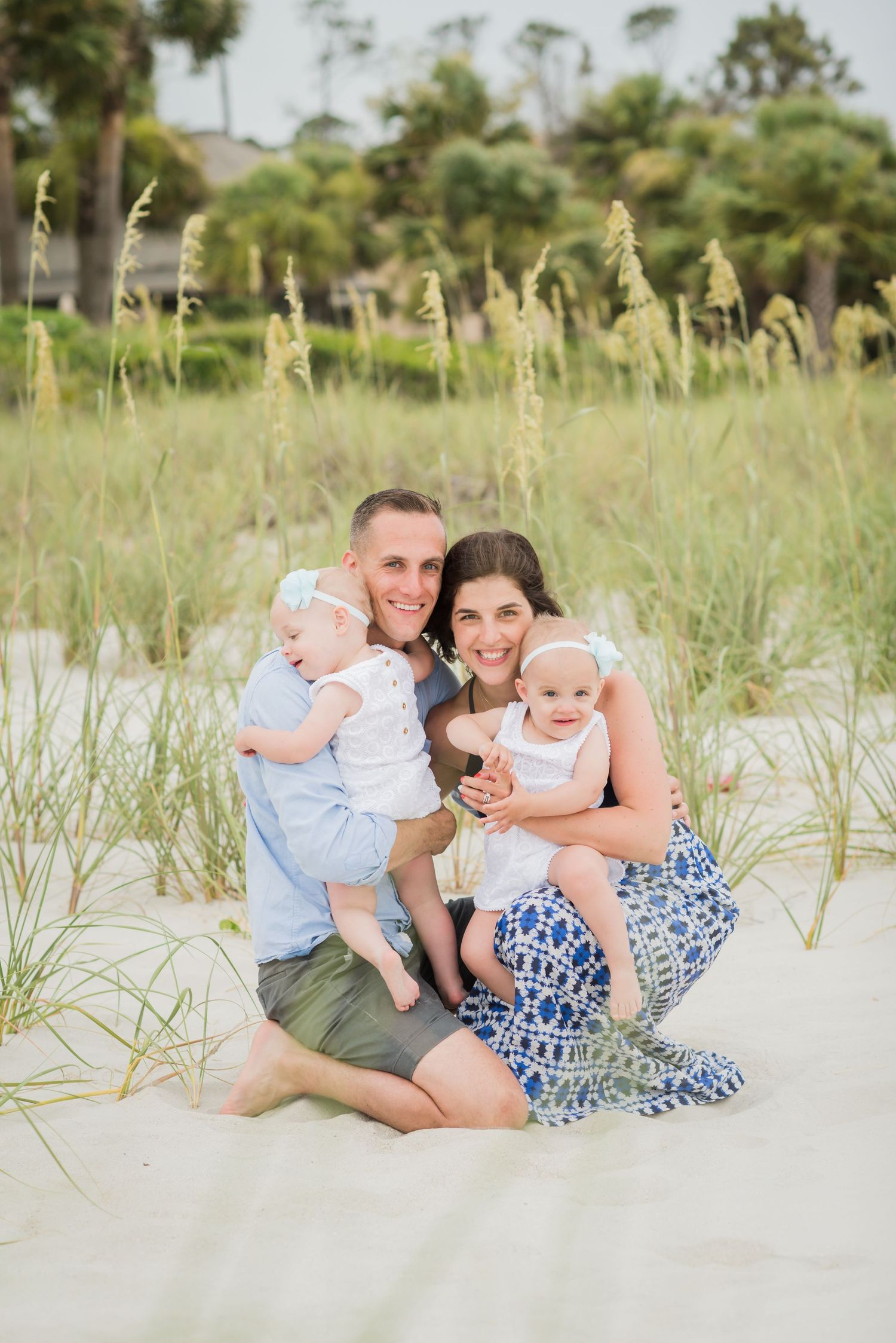 Family group relaxing together in beach sand dunes with sea grass. Palm, Coast Florida family portrait.