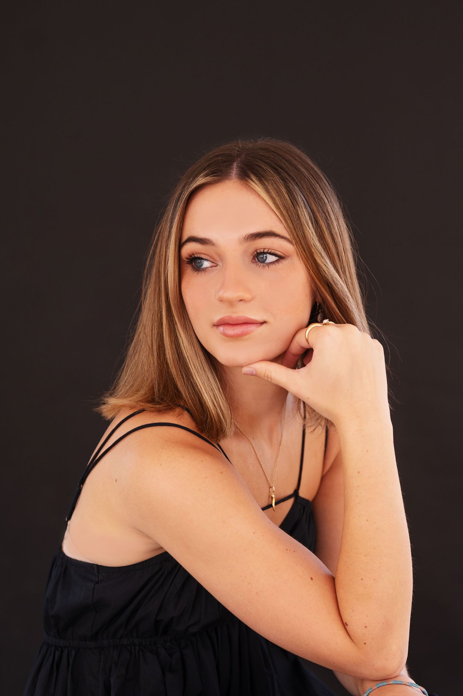 Artistic portrait series against dark background featuring model in black top with soft lighting.