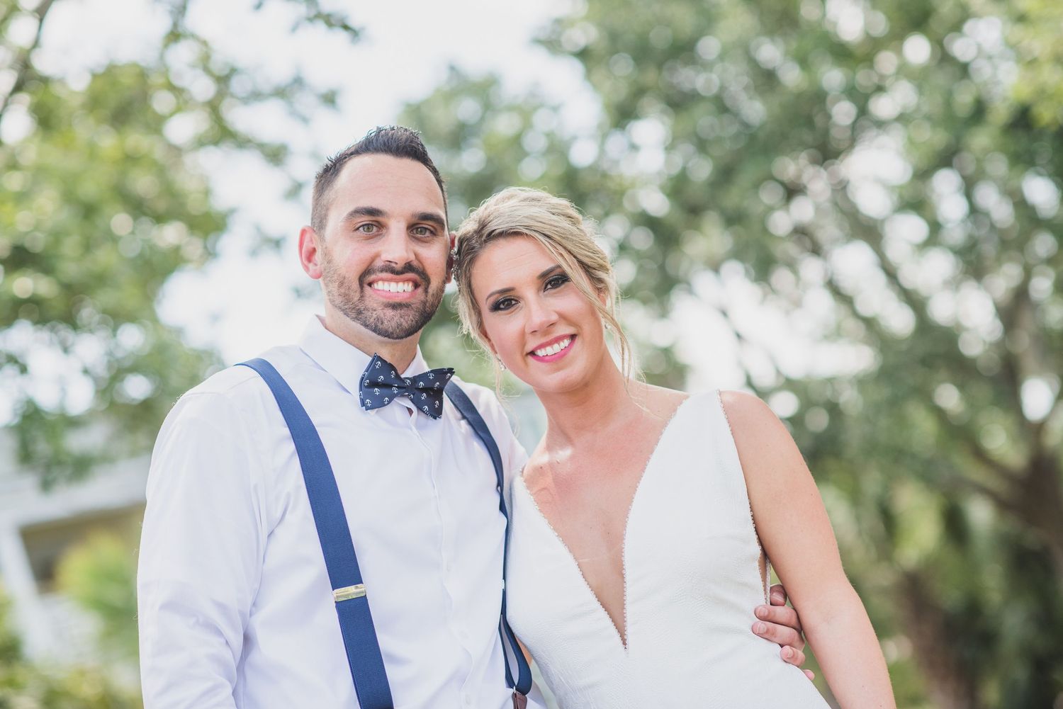 A bride and groom share intimate moments during an outdoor wedding photoshoot with natural greenery in the background.