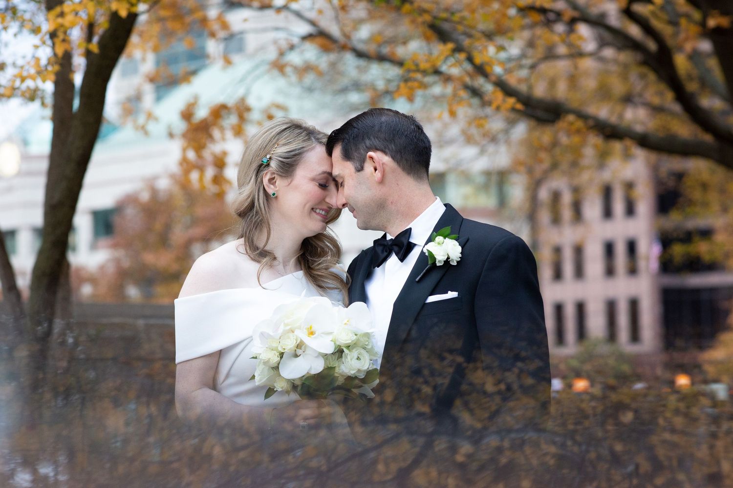 Romantic autumn wedding portrait with fall foliage in background.
