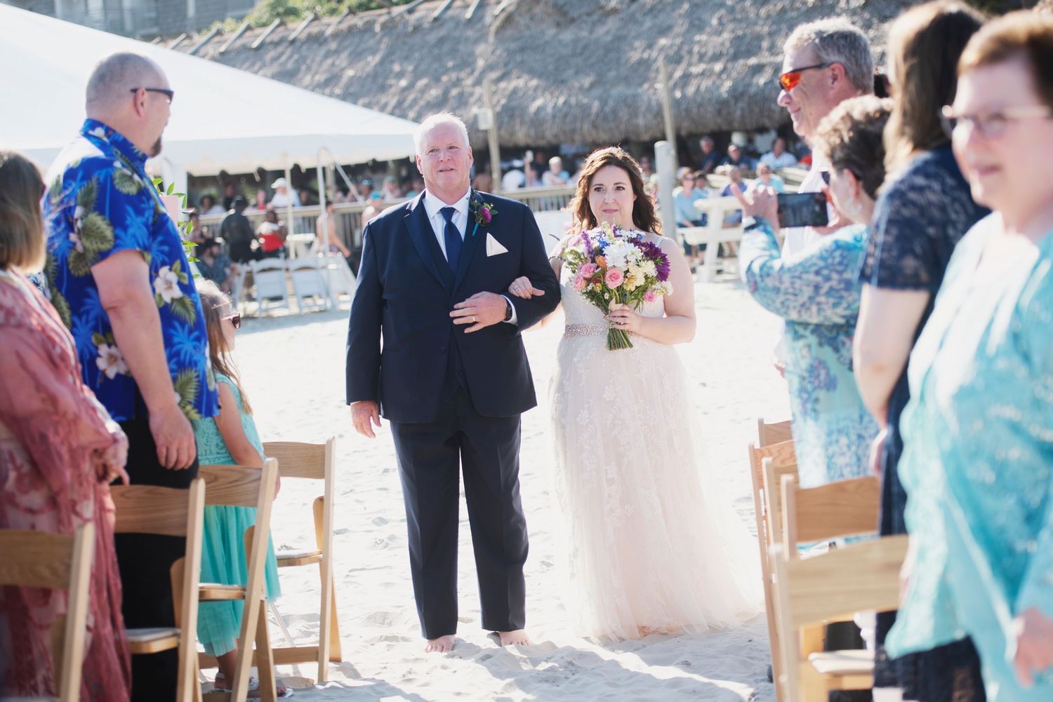 Wedding reception under white tent with turquoise decor on beach.