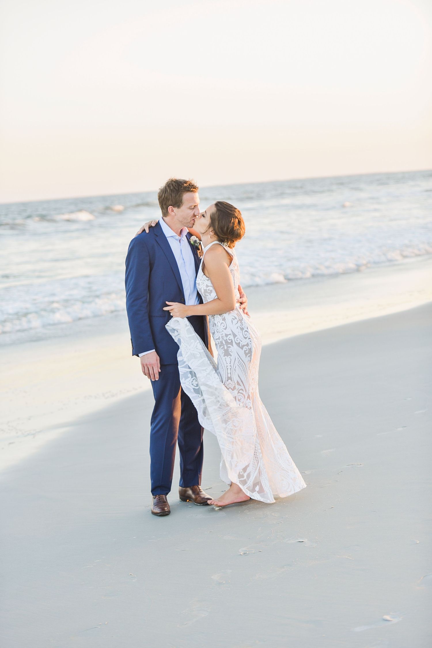 A romantic couple embraces on a serene beach at sunset wearing formal attire. Hammock Beach engagement session.