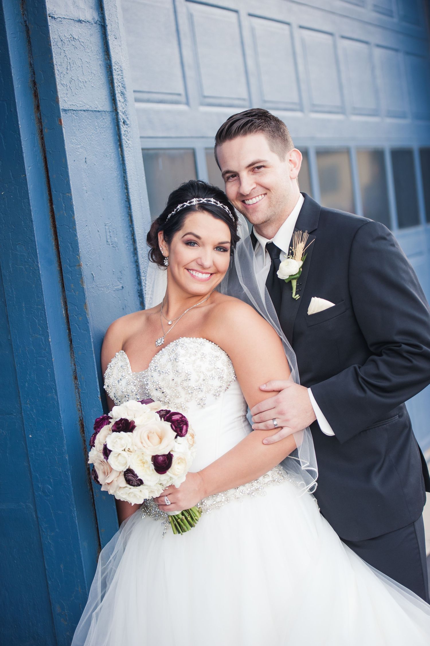 A romantic wedding portrait series against a blue wall with a couple in formal attire and white floral bouquet.
