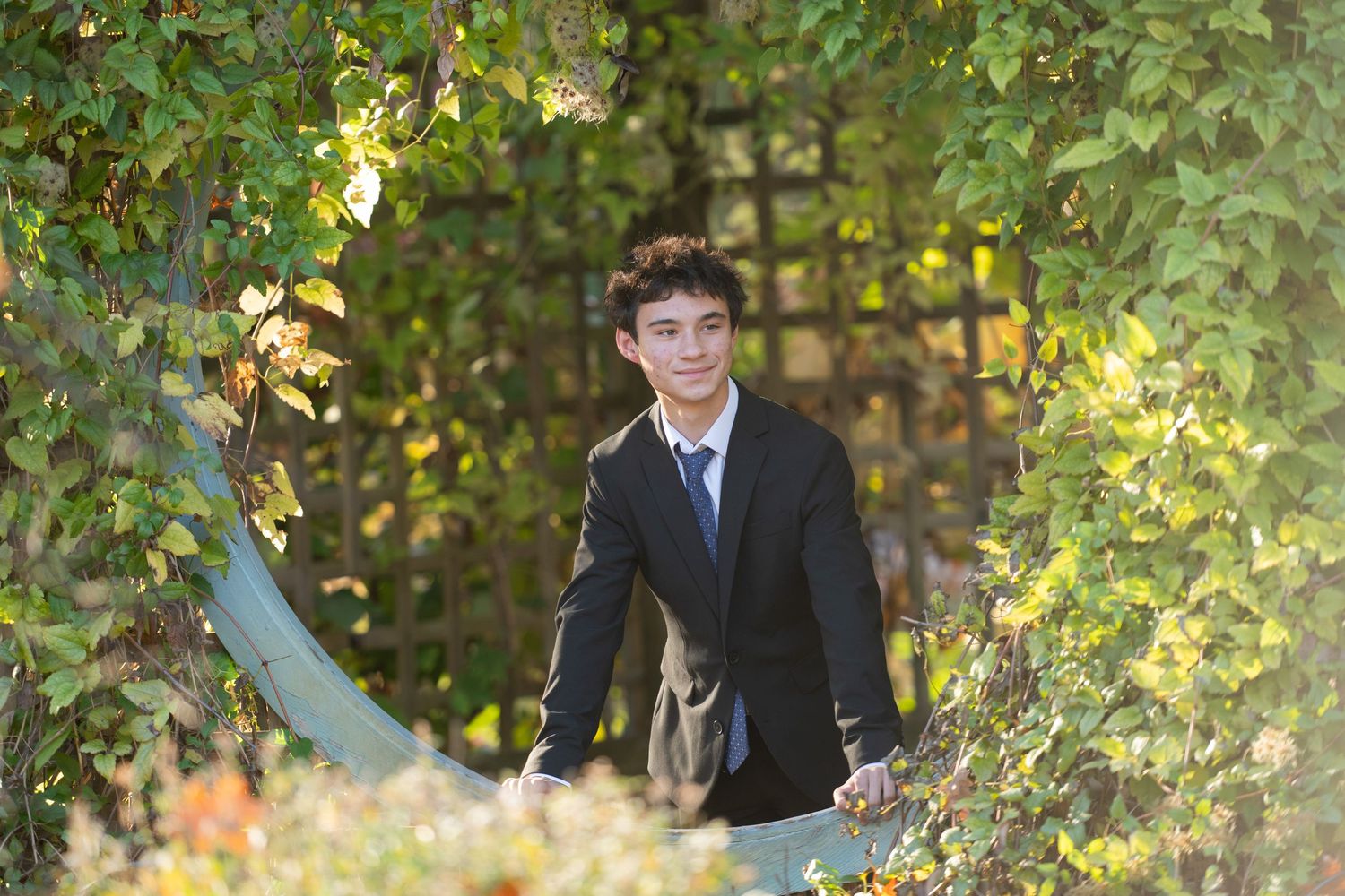 A couple in formal attire poses together in a lush garden setting during a wedding photoshoot.