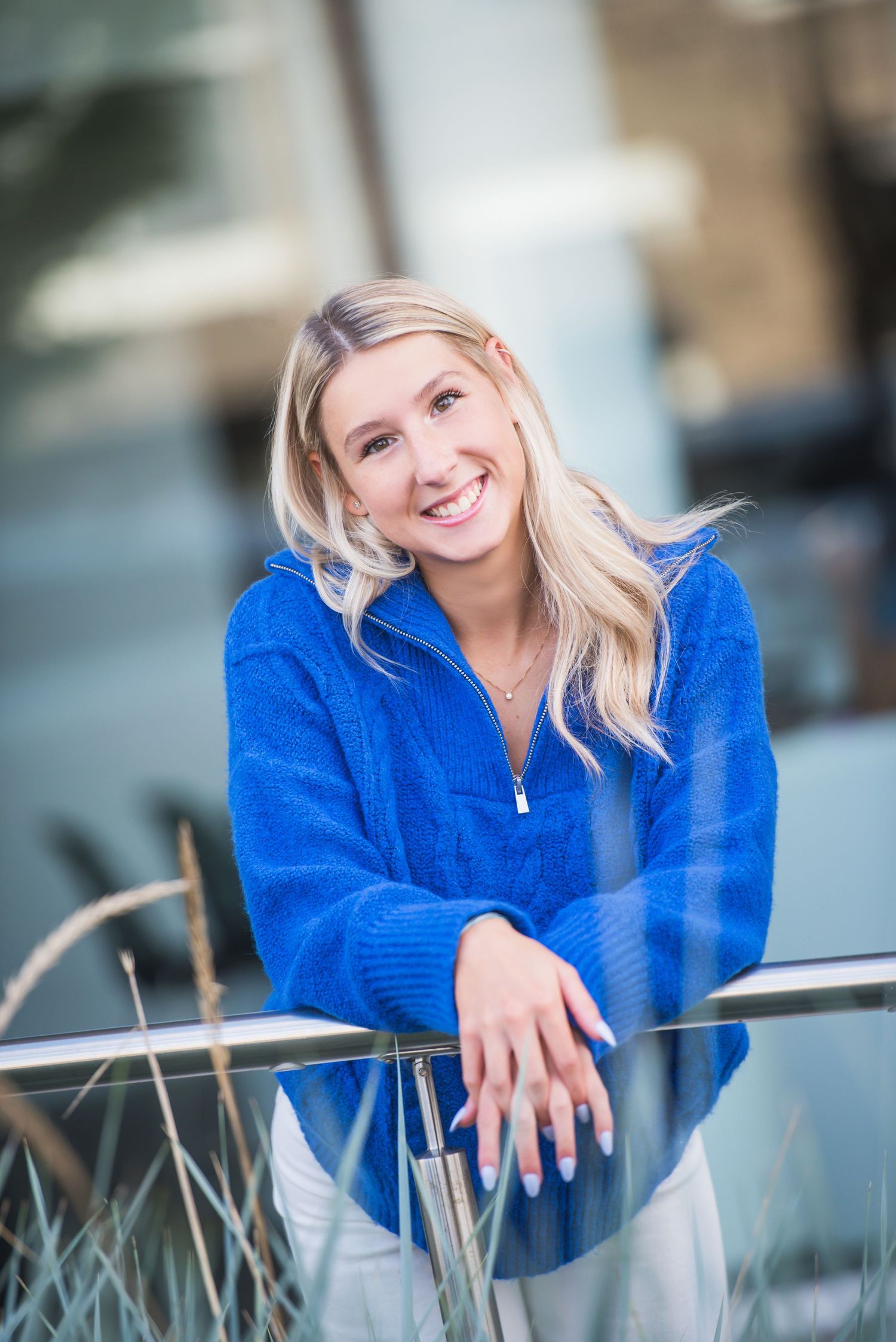 Casual outdoor photoshoot showcasing a vibrant royal blue sweater against modern architecture.