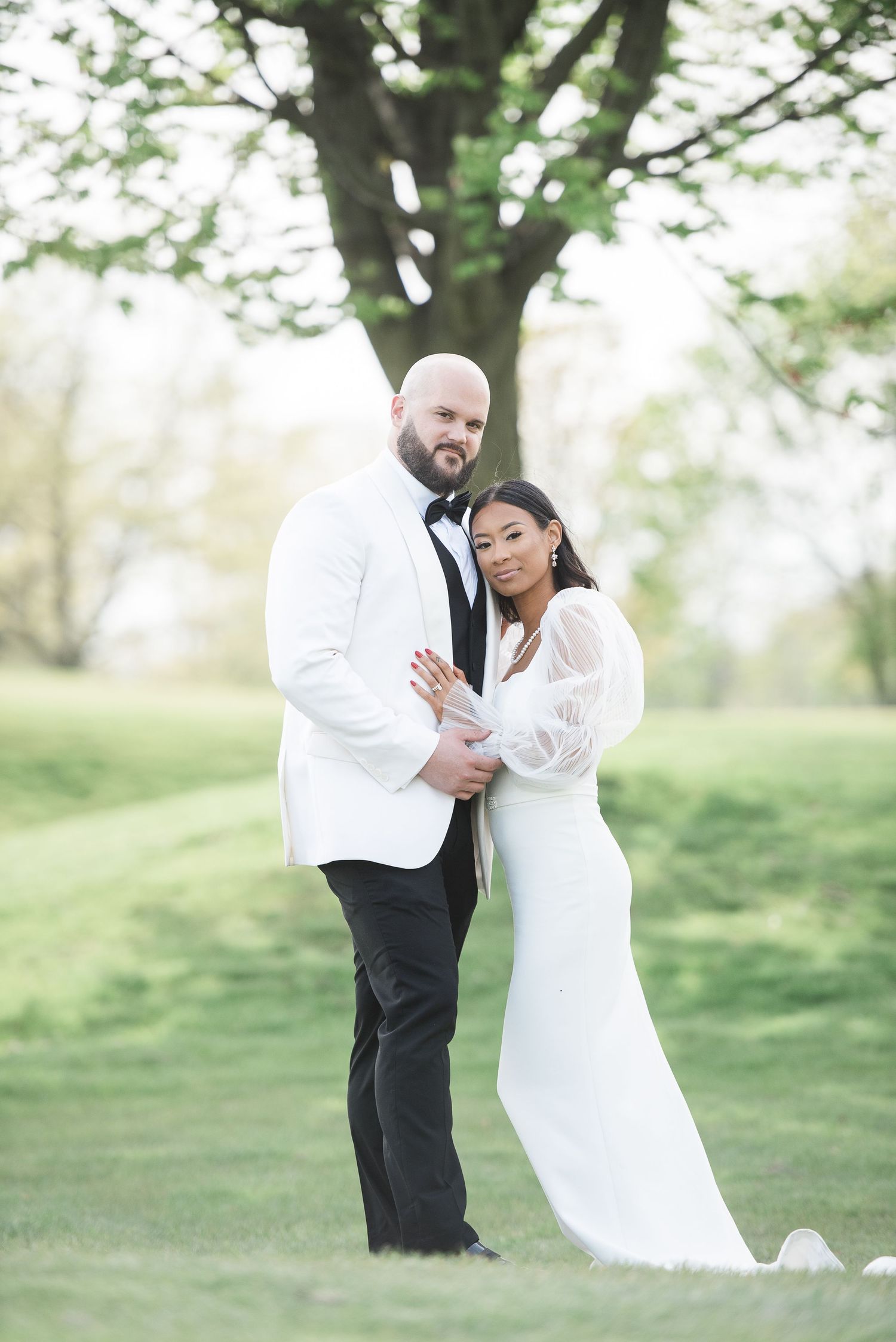Wedding couple in formal attire sharing intimate moment outdoors in spring setting.