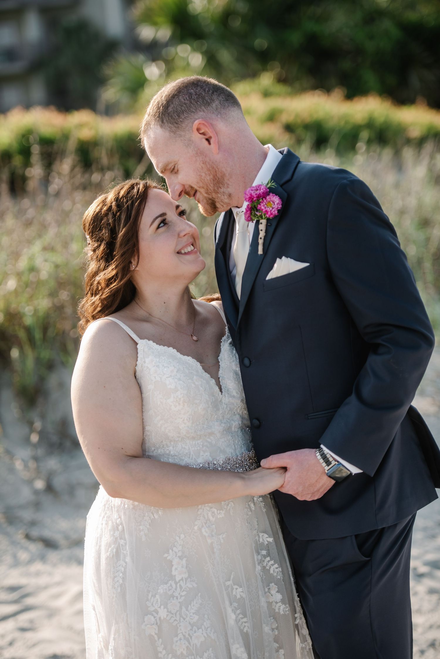 Joyful wedding couple sharing intimate moments on a sandy beach at sunset.