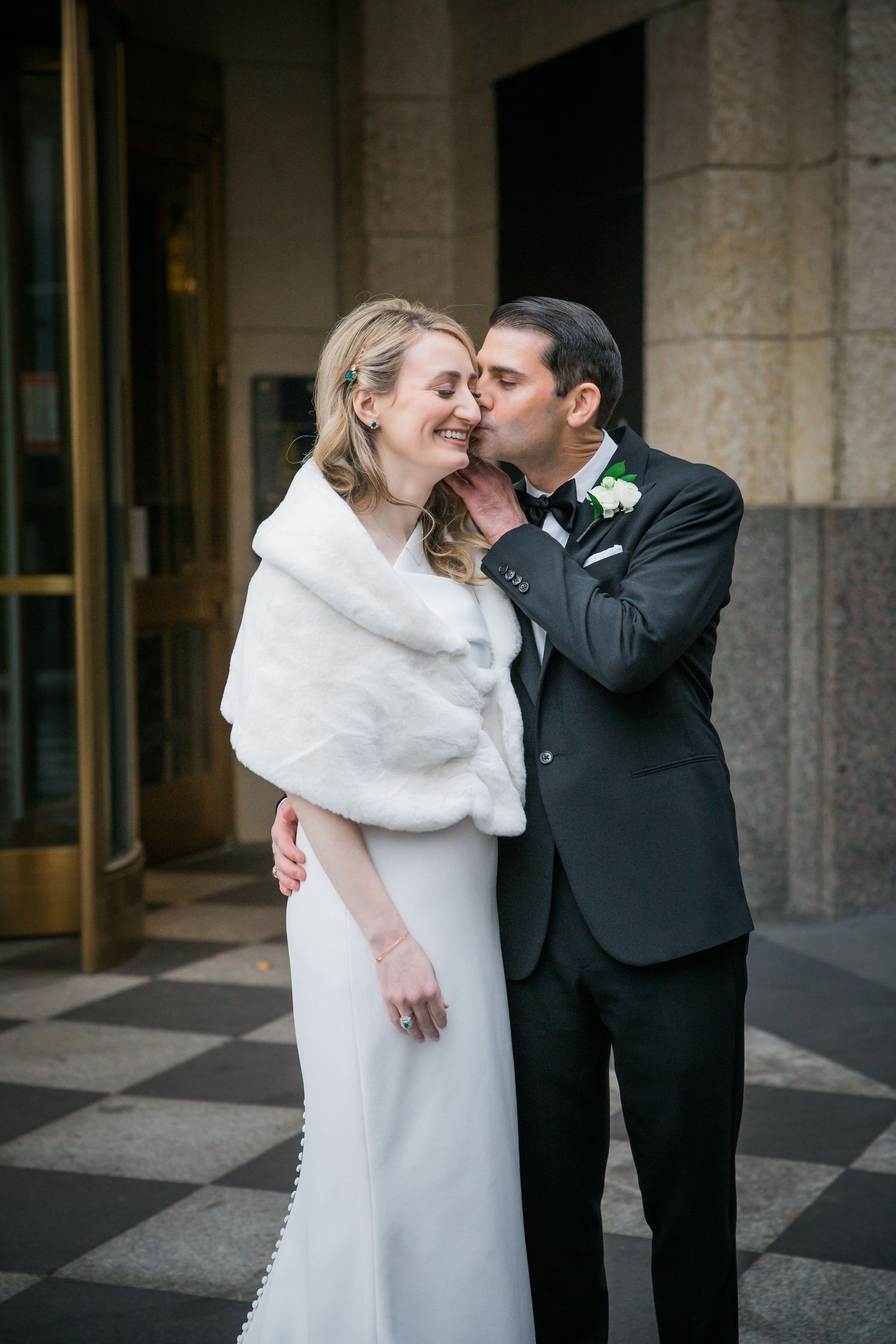 Romantic moment between newlyweds outside a stone building.