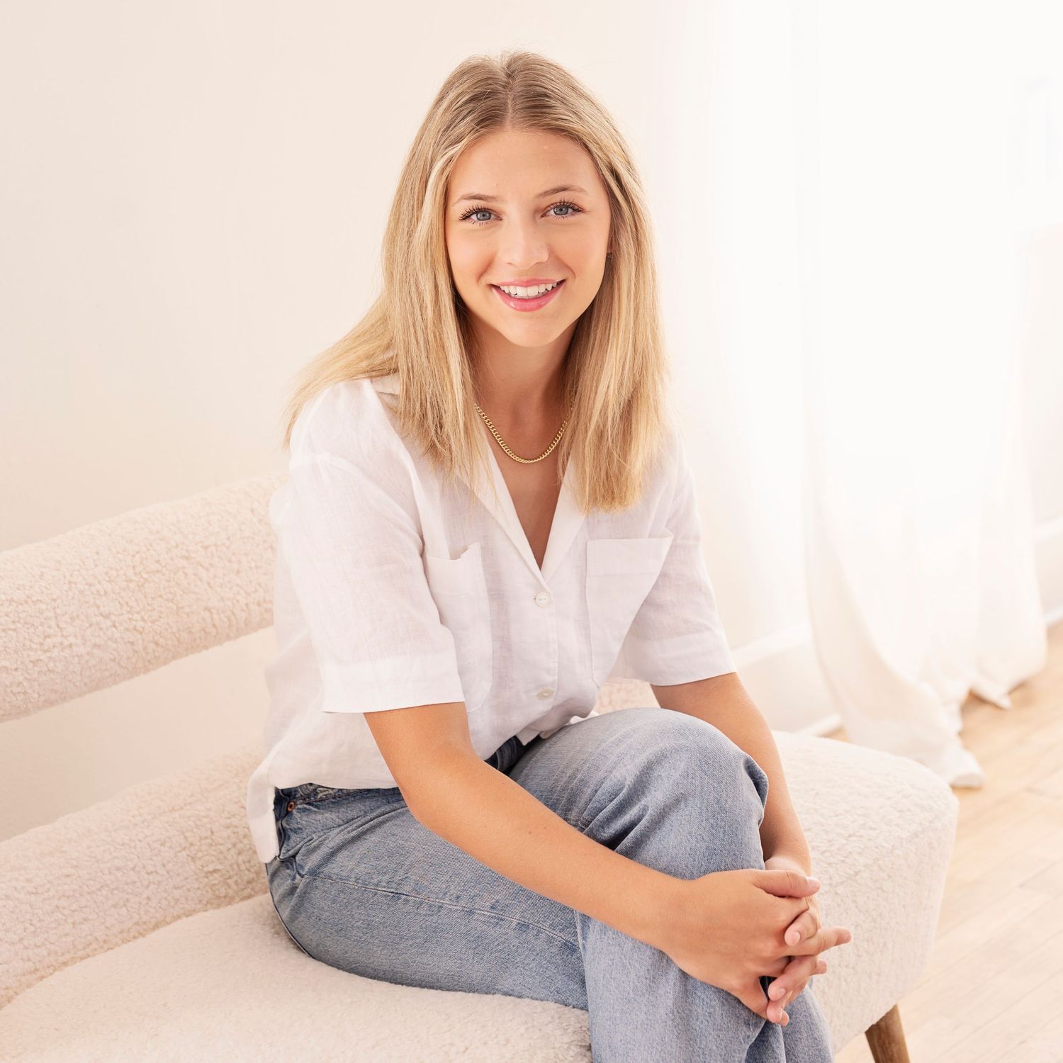Model in casual white t-shirt and jeans poses against light background in lifestyle photoshoot series.