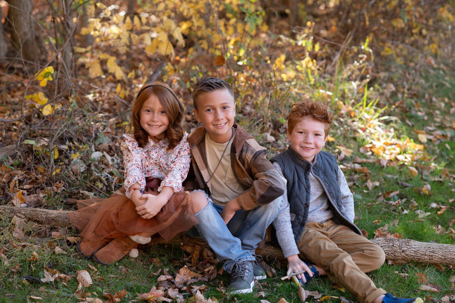 Family enjoying autumn day together on fallen leaves in outdoor setting with their brown dog.