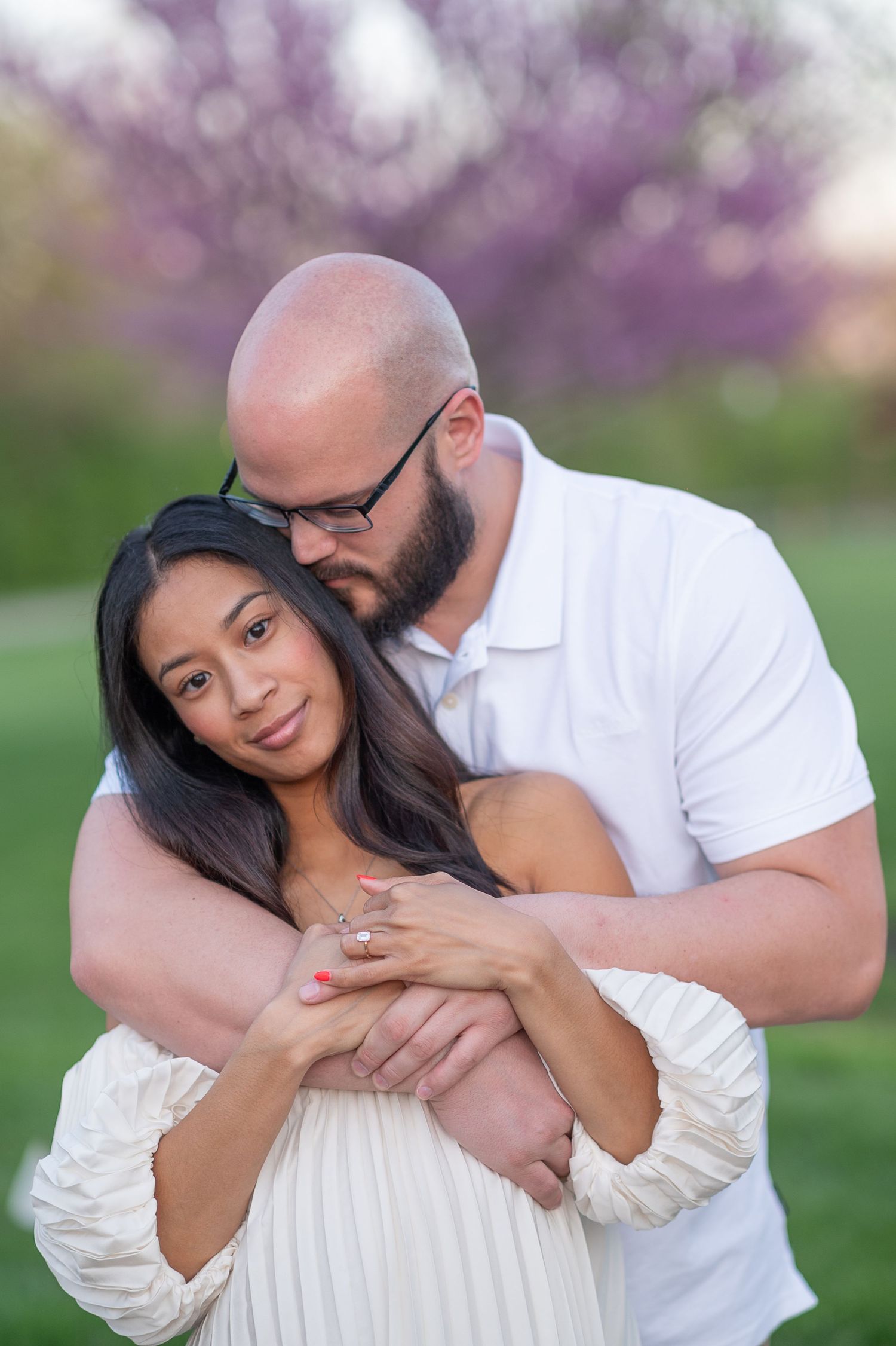 Ohio engagement session Romantic couple embraces in a spring garden with blooming cherry blossoms in the background.