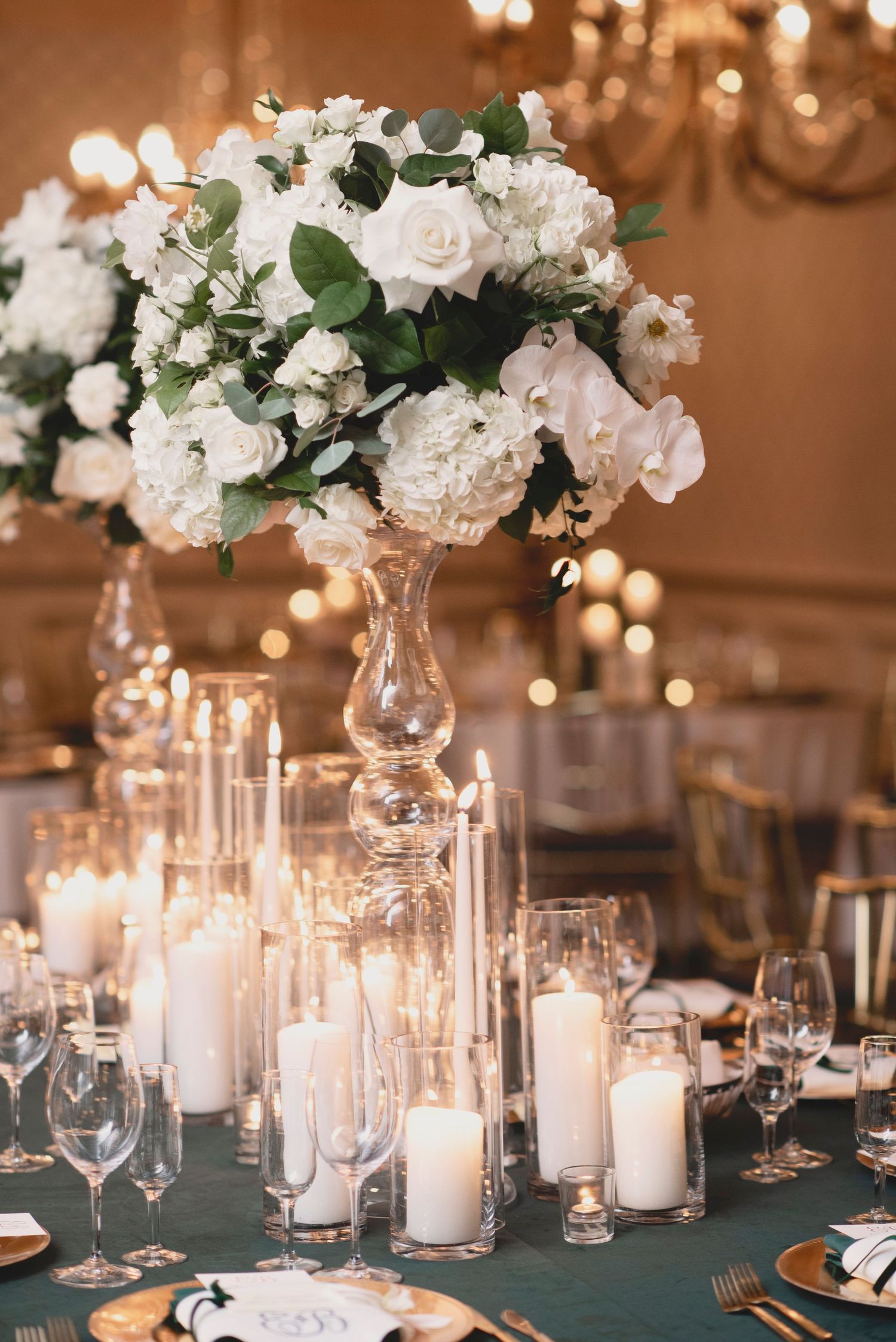 Elegant wedding reception table decor with white floral centerpieces, candles and crystal glassware.