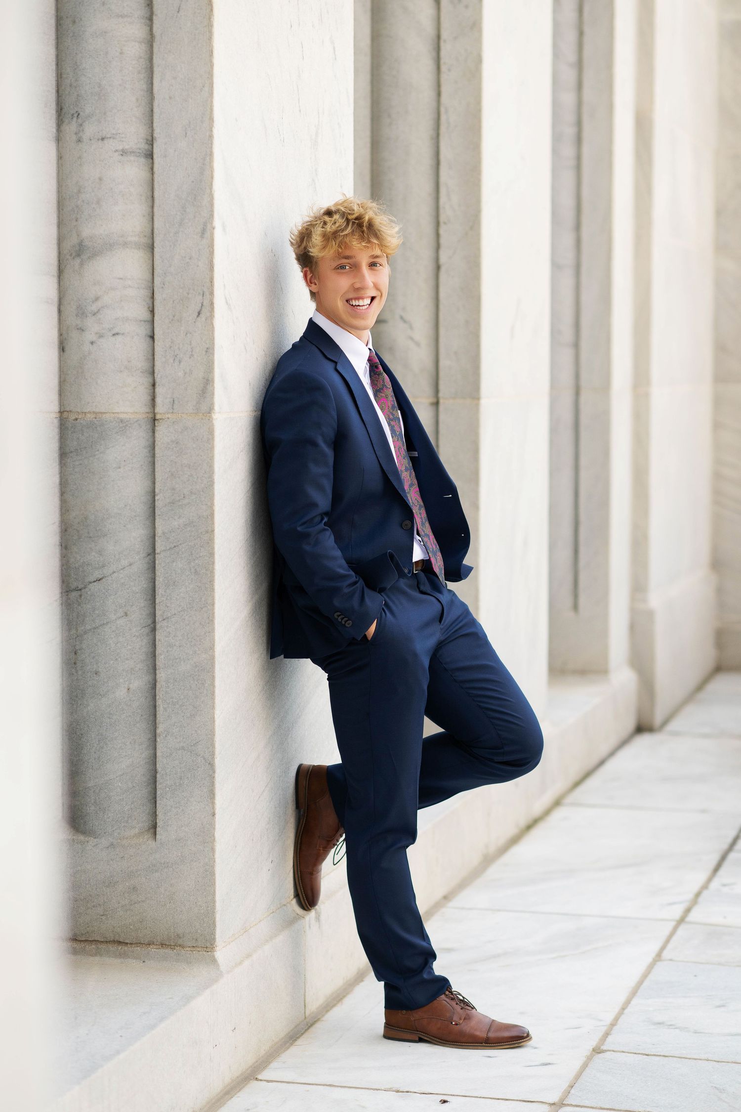 Three sequential photos show someone in a navy suit leaning against white marble columns in an architectural setting.