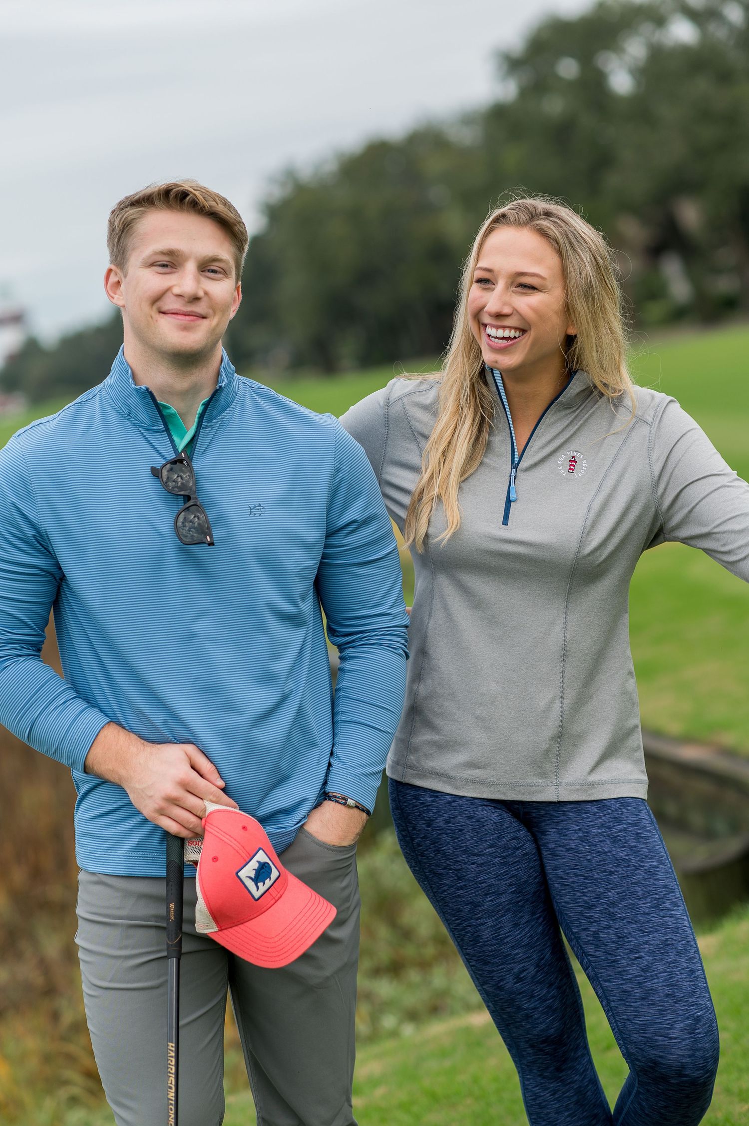 Couple in athletic wear sharing playful moment outdoors with golf carts visible.Sea Pines Hilton Head. Southern Tide Brand editorial photosh