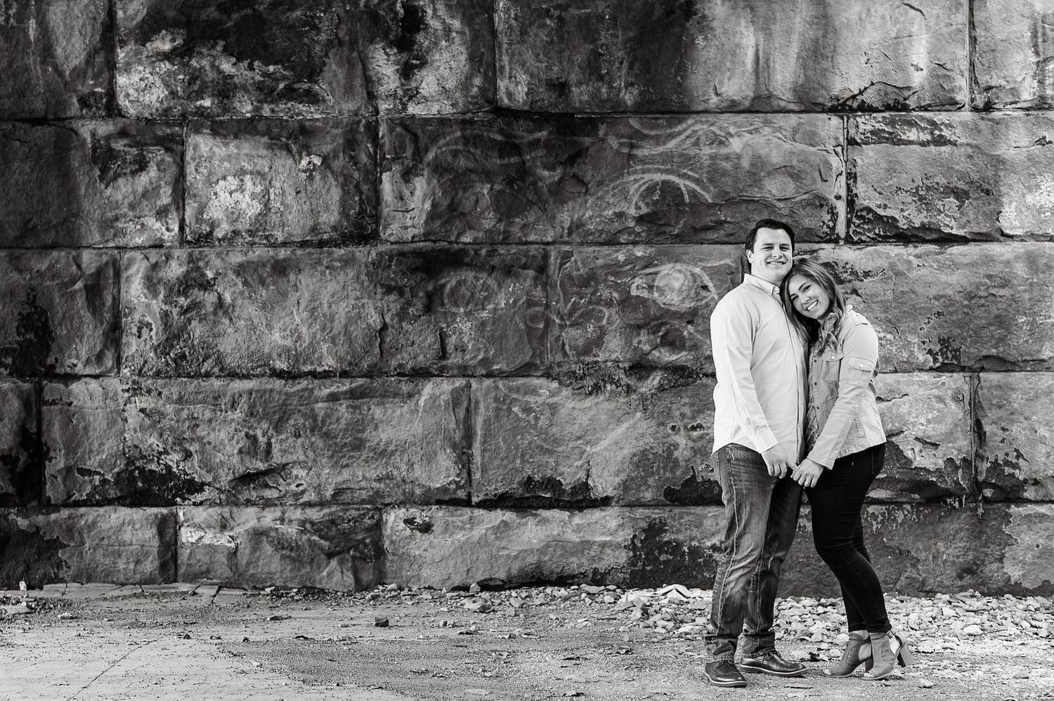 Black and white portrait session against a textured stone wall backdrop.