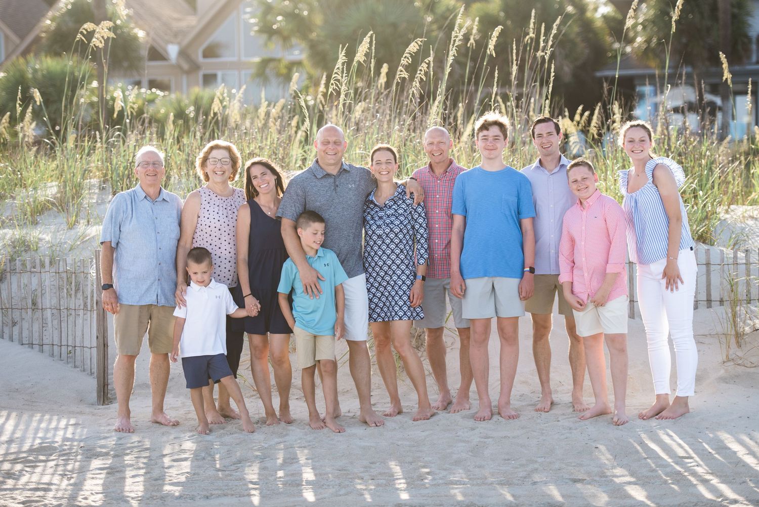 Large group photo on coastal boardwalk with sea oats and dunes in background.