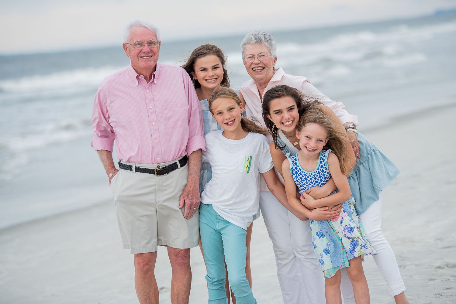 A multi-generational family group poses together on a sunny beach wearing casual summer attire.Hammock Beach, Sea Pines coastal photography.