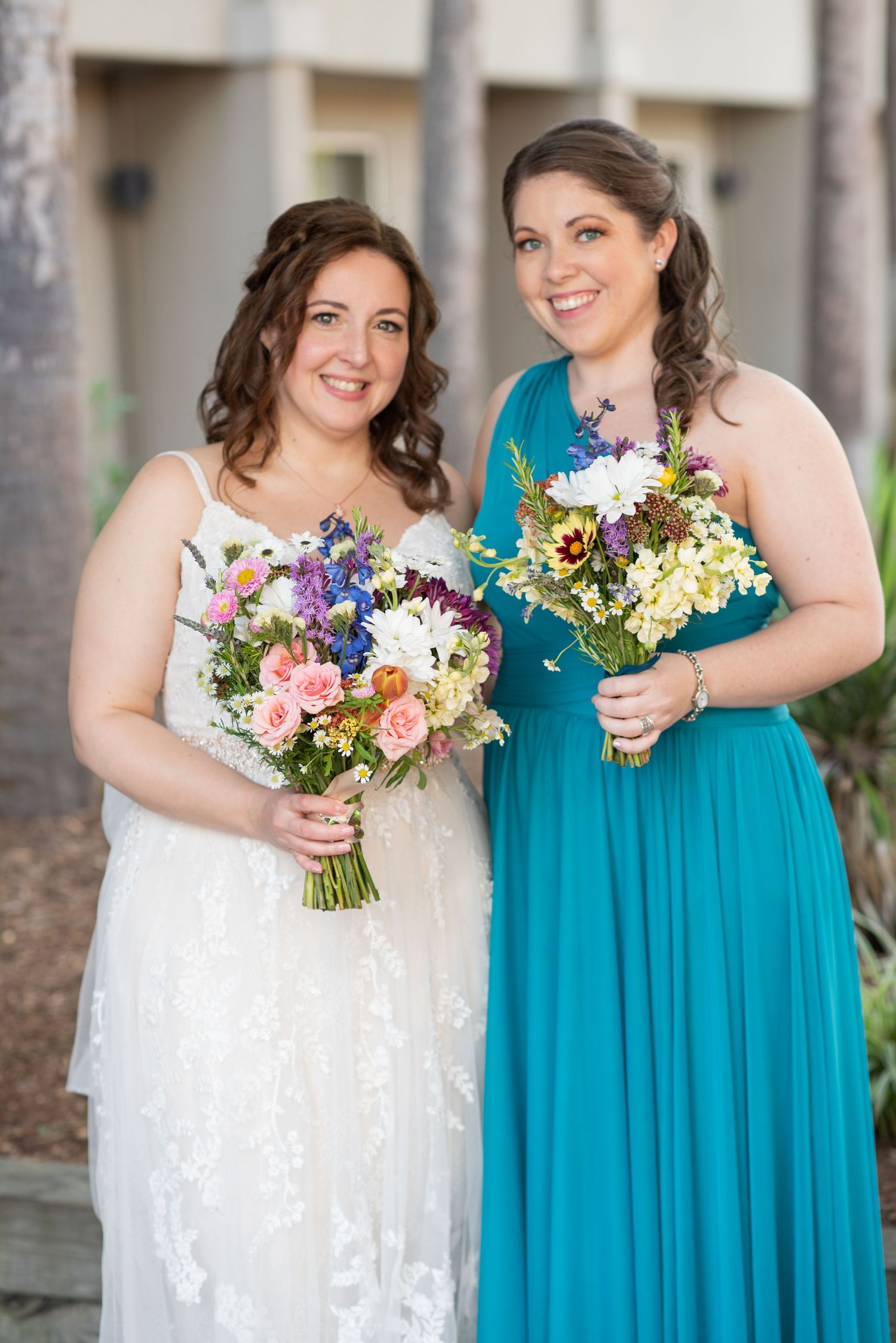 Wedding party wearing teal blue dresses holding colorful wildflower bouquets.
