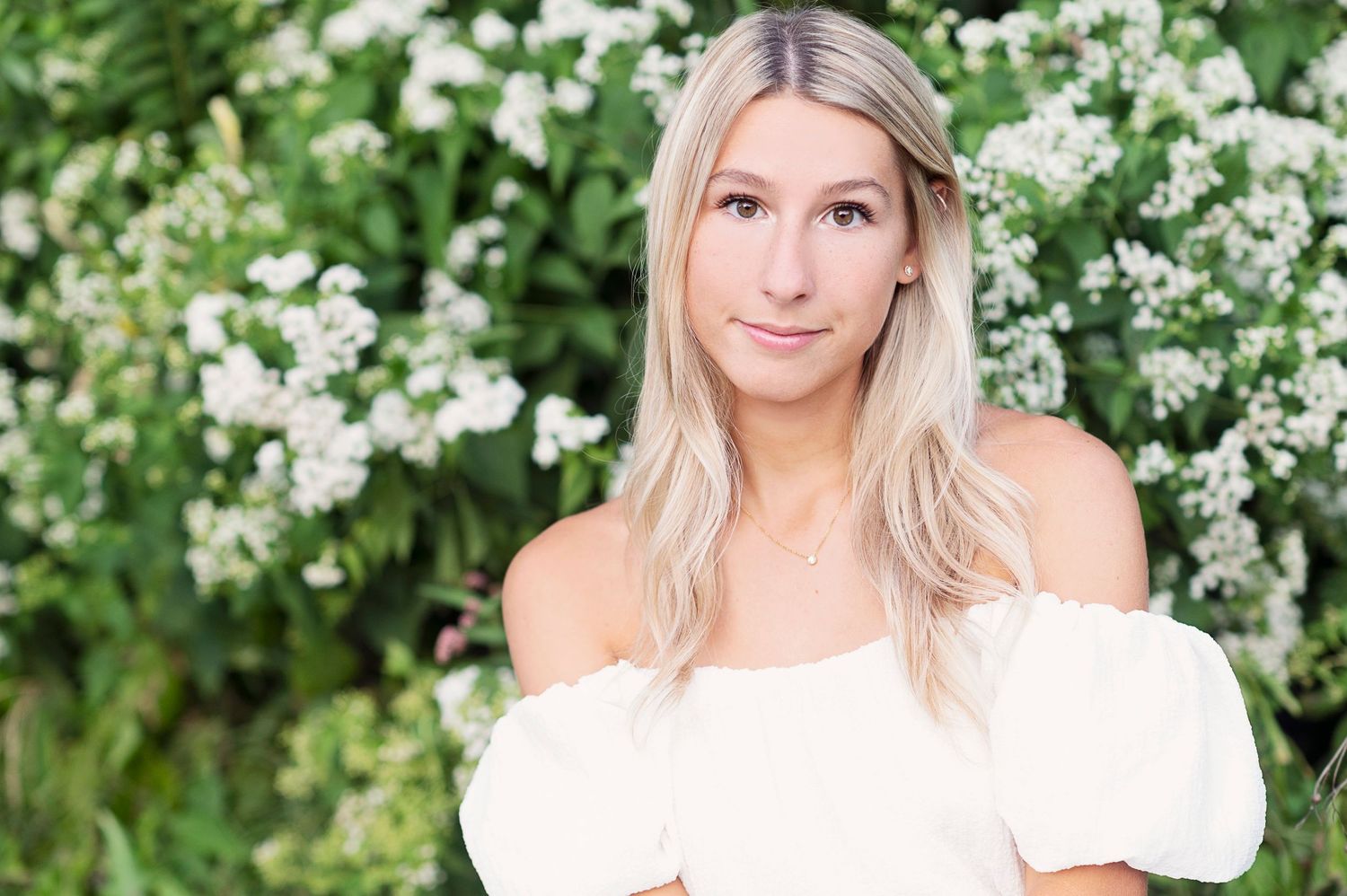 Portrait in white off-shoulder dress against flowering bush background. Columbus, OH senior.