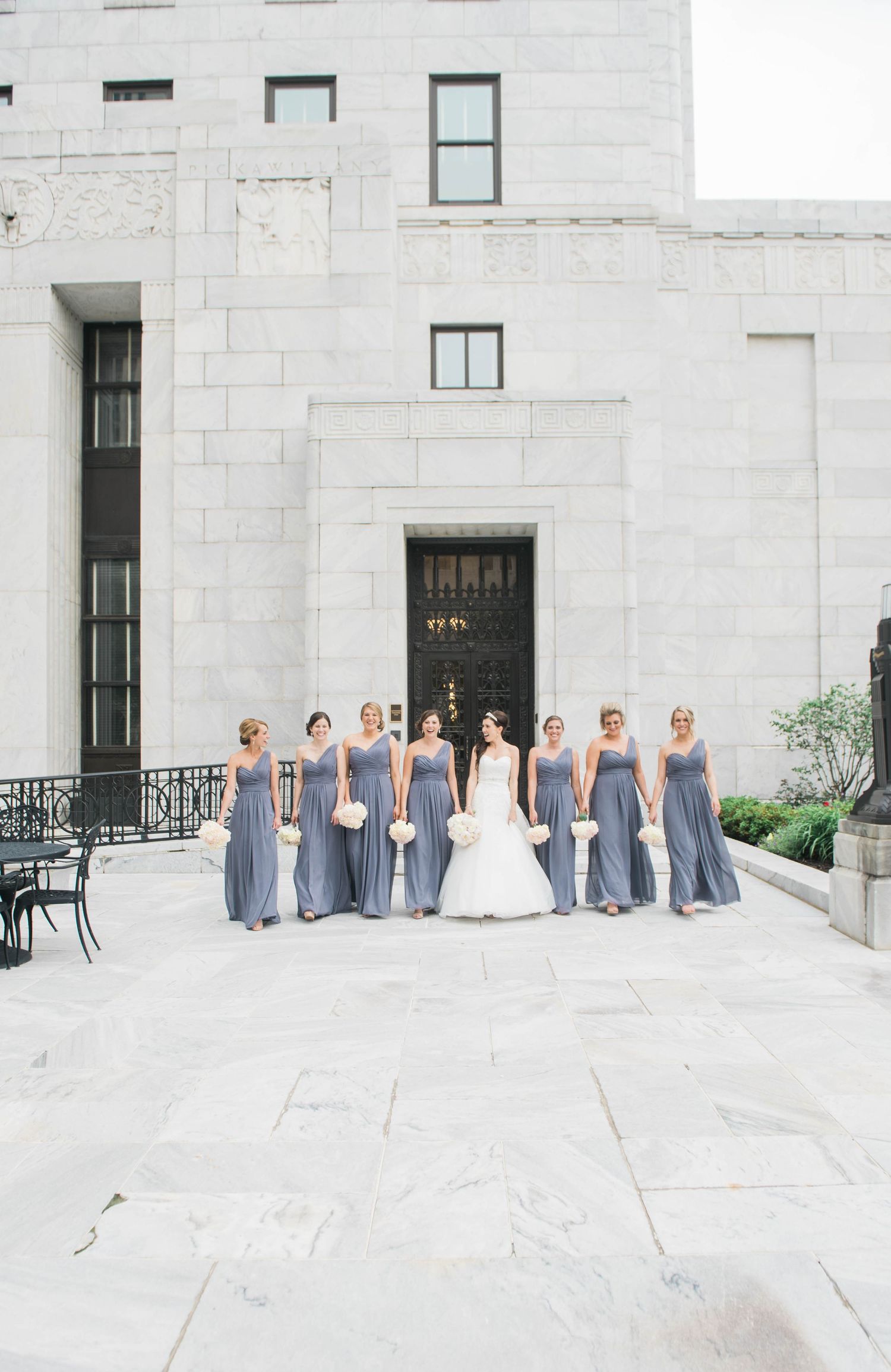Columbus Ohio Wedding party in gray dresses lined up against a white stone building exterior.