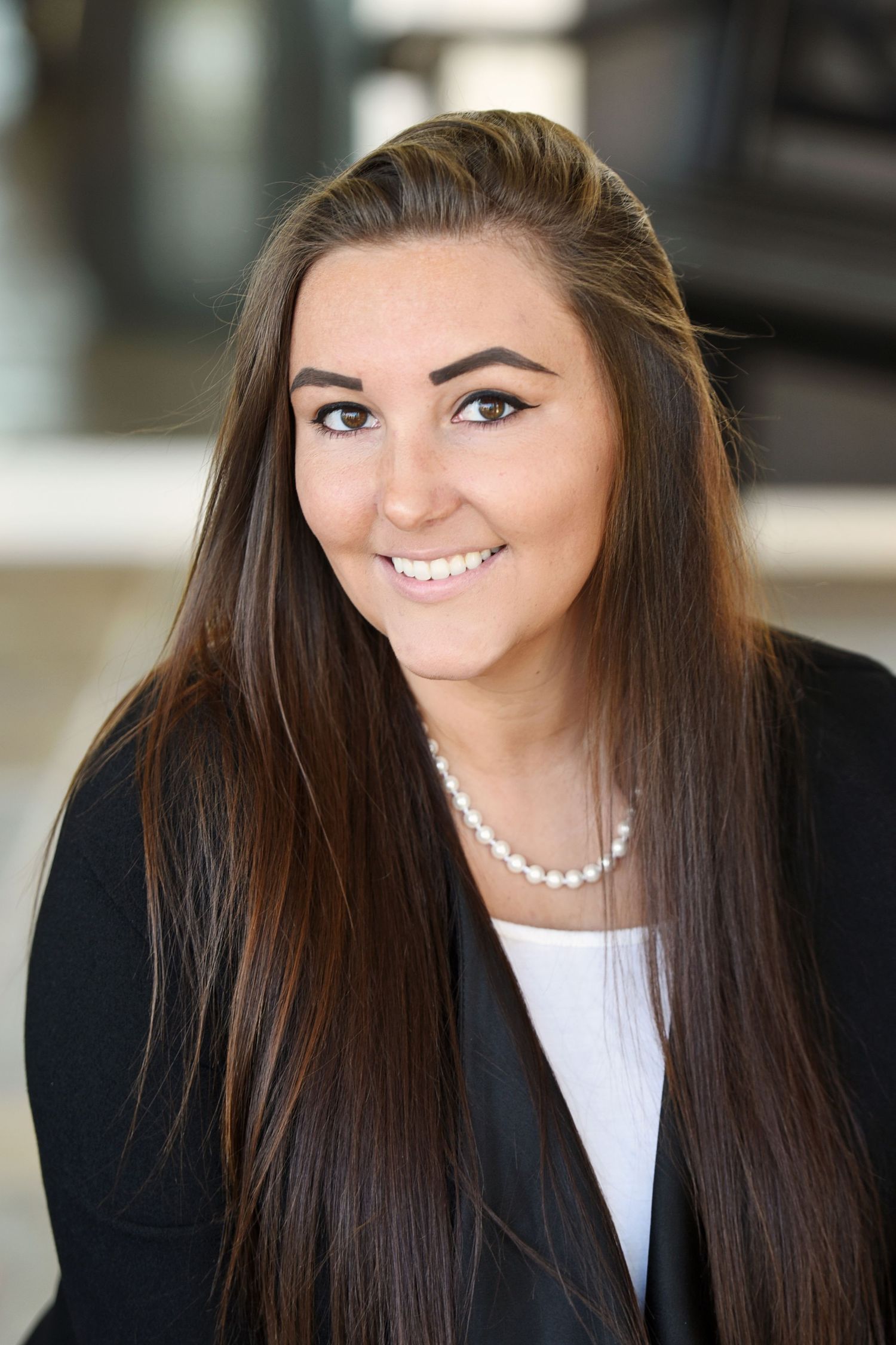 Professional portrait series featuring dark business attire and pearl necklace.