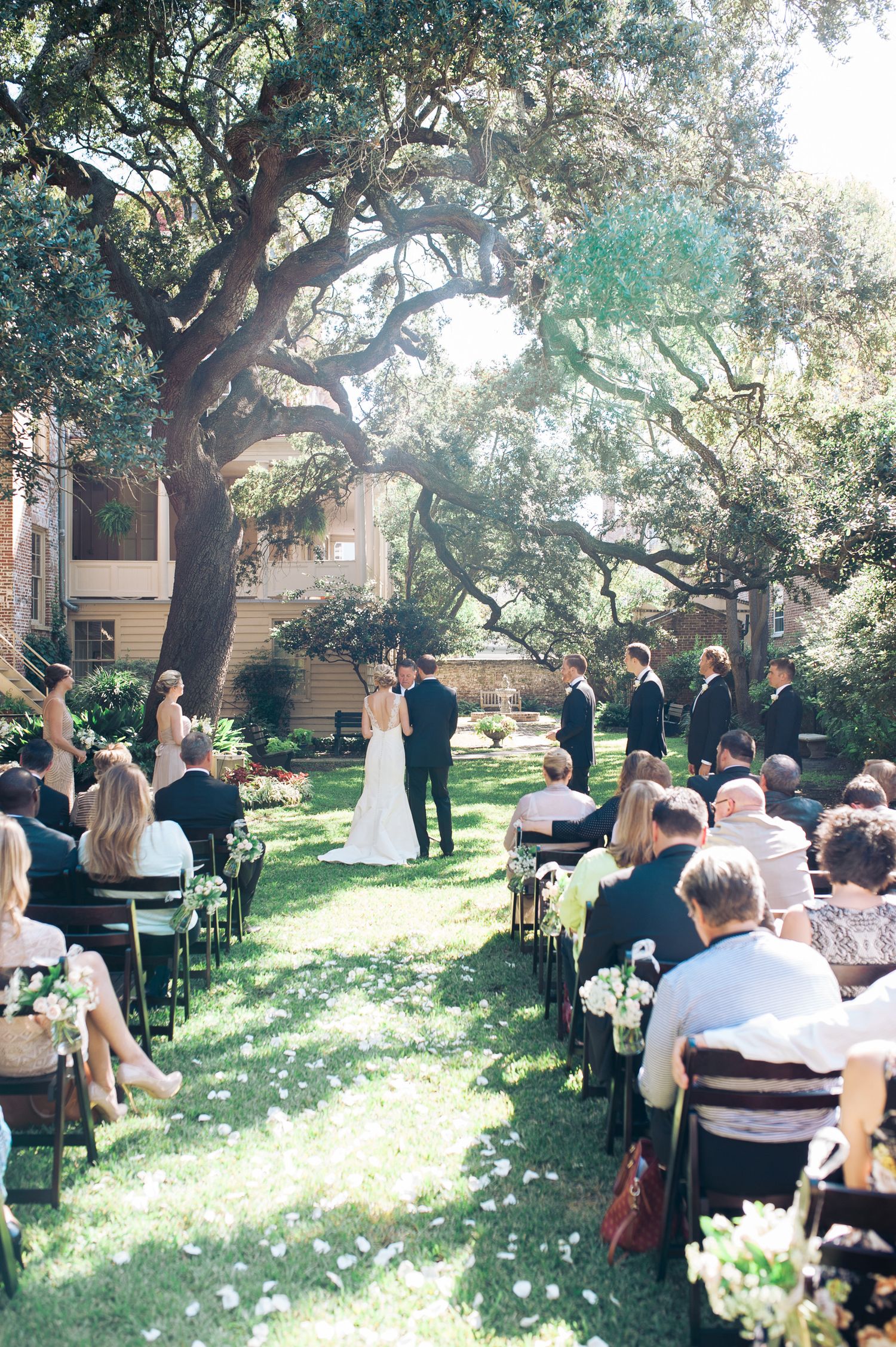 Wide view of an intimate garden wedding ceremony with guests seated beneath sprawling oak trees. Washington Oaks