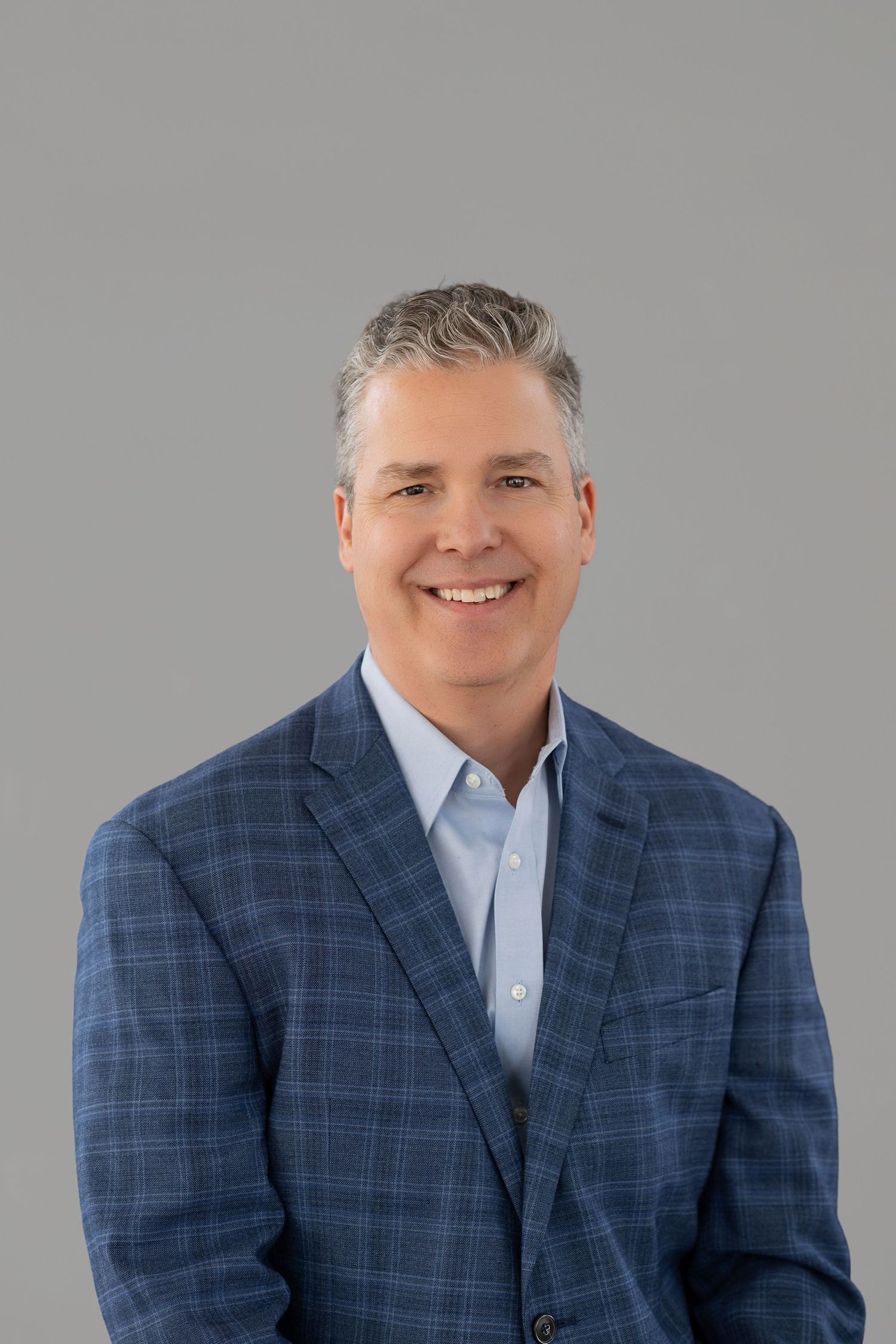 Professional headshots of a man in a blue plaid blazer and white shirt against a gray background.