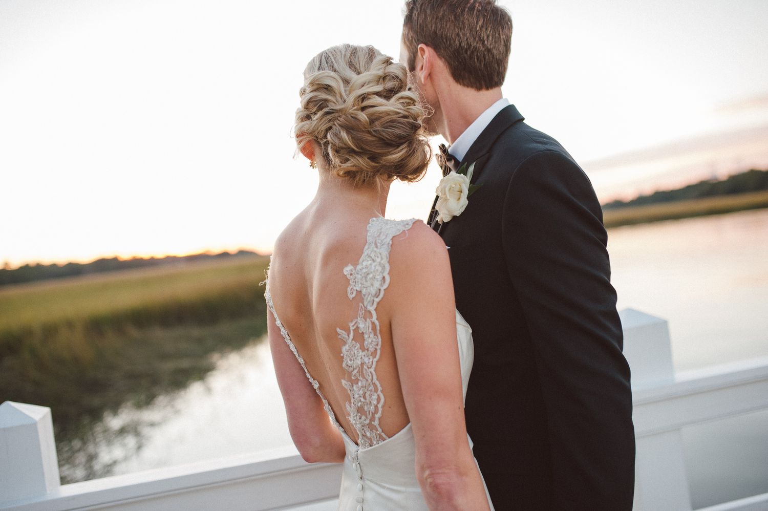 Coastal Bride and groom share an intimate moment at sunset by the water's edge during their romantic outdoor wedding.