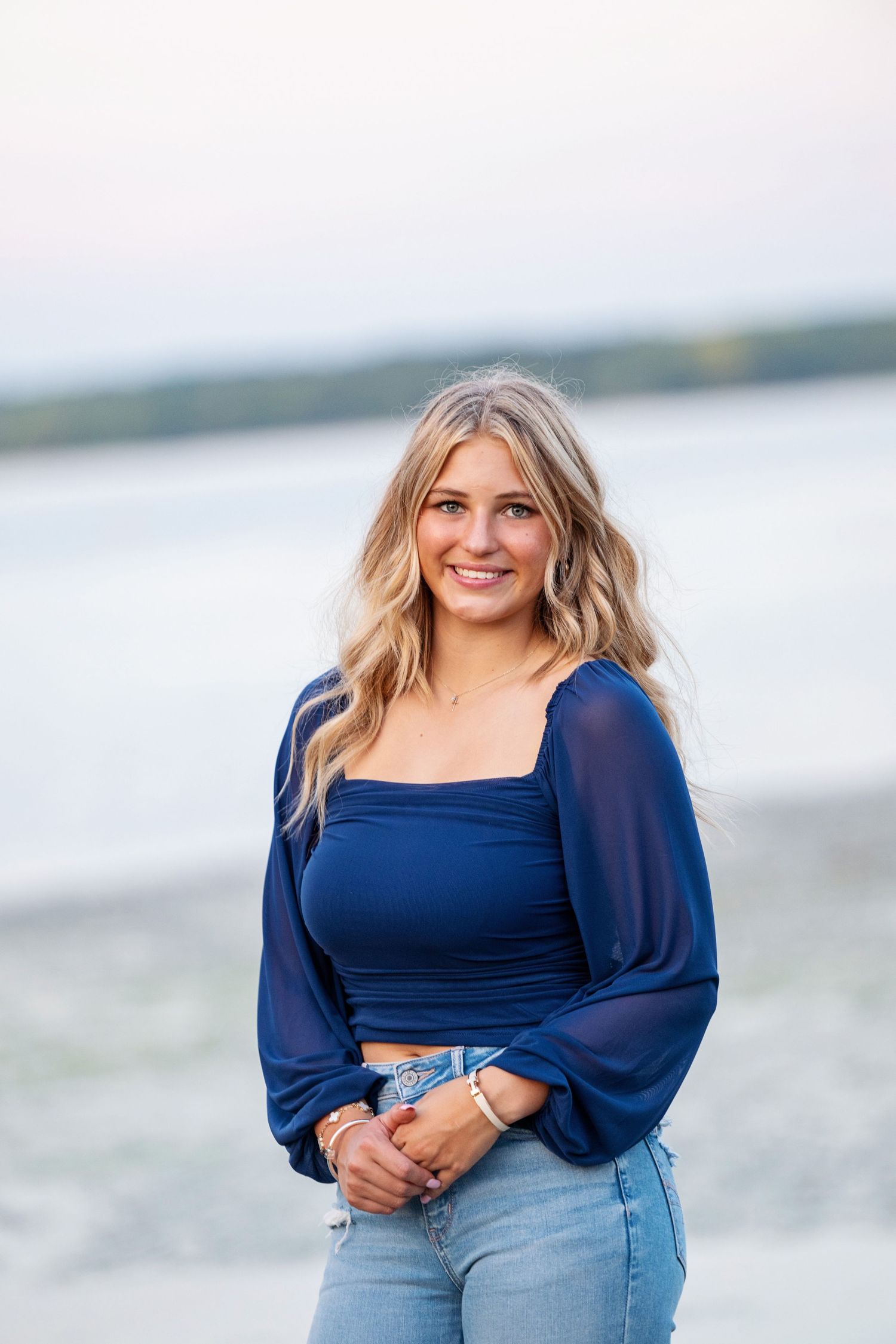 Woman in navy blue top poses casually by the waterfront at sunset. St. Augustine Senior Portrait Session.