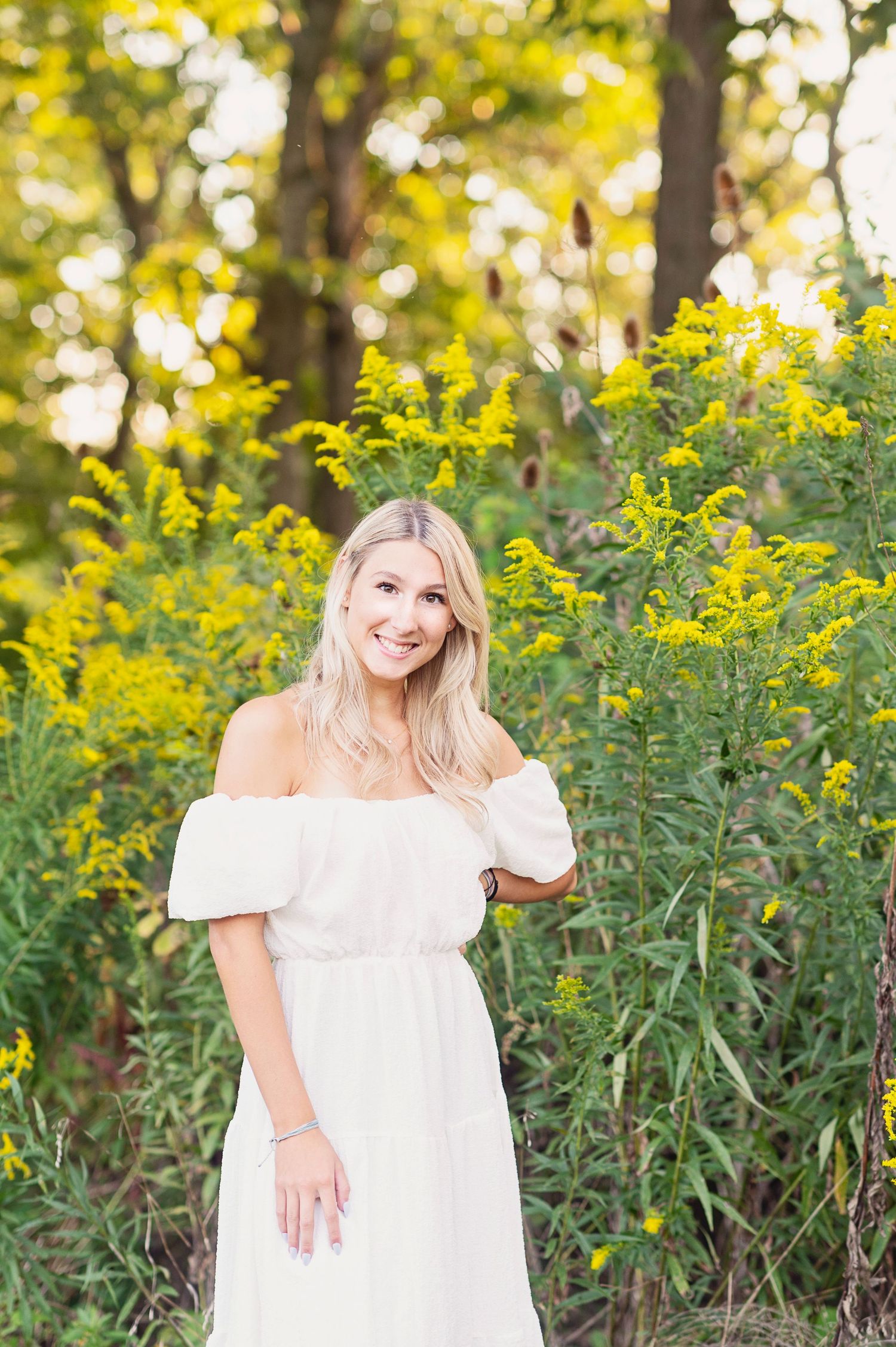 A dreamy outdoor portrait surrounded by tall yellow wildflowers in late summer light.