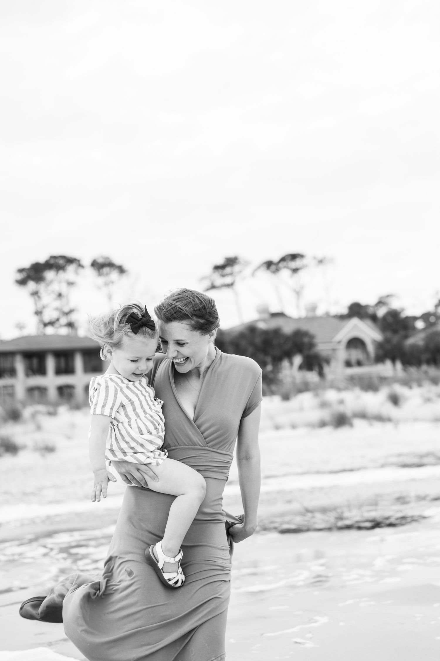 Black and white photo of parent and child sharing tender moment on beach. St. Augustine Beach, Hammock Beach photographer.