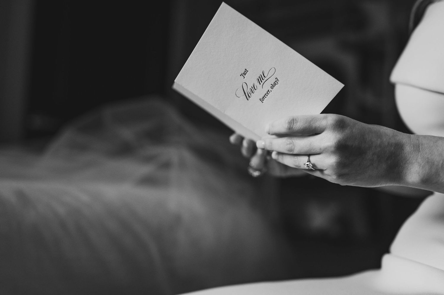Black and white photo of hands holding a wedding note card.