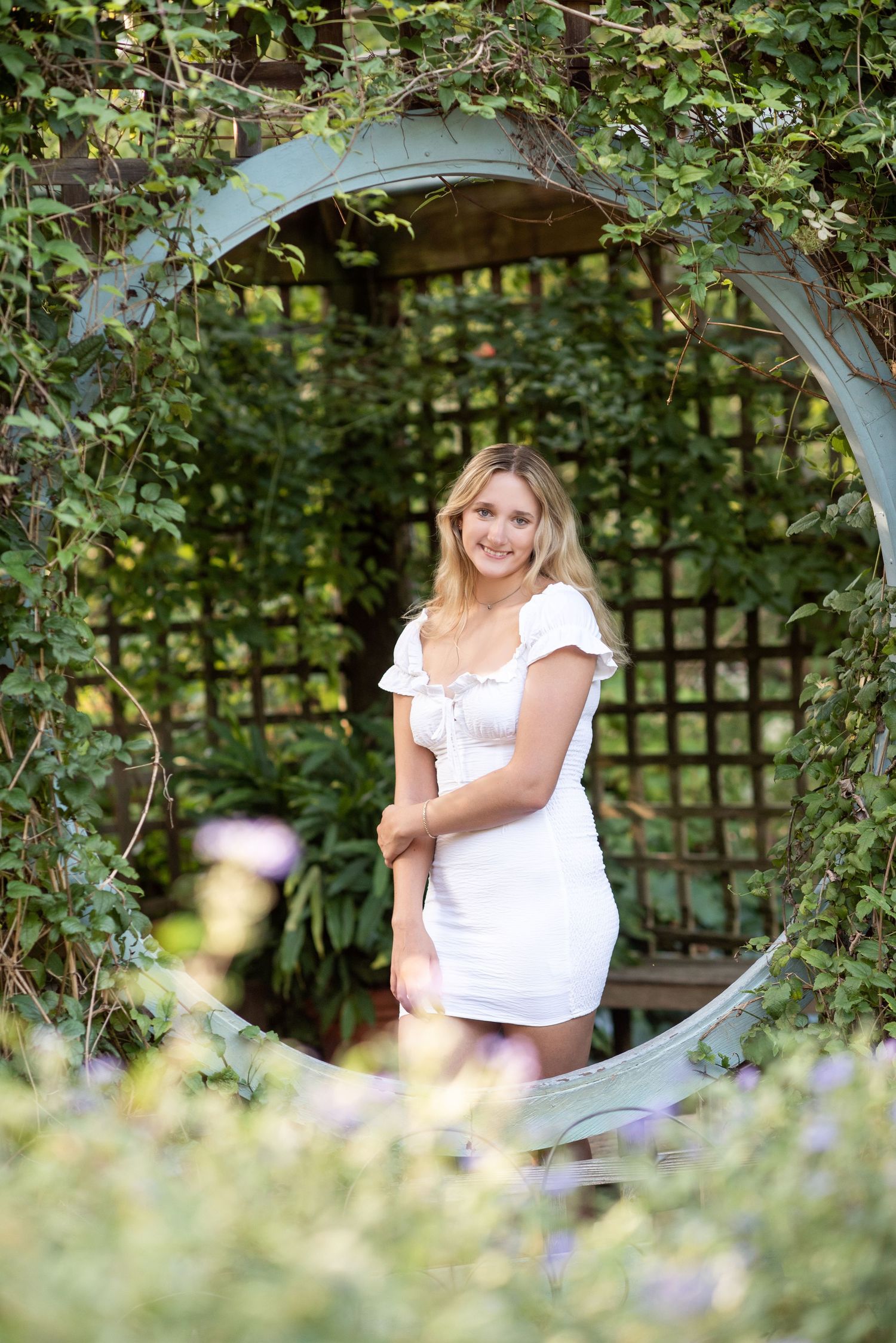 A series of outdoor garden photos showing someone through a decorative white arch surrounded by lush greenery and foliage.
