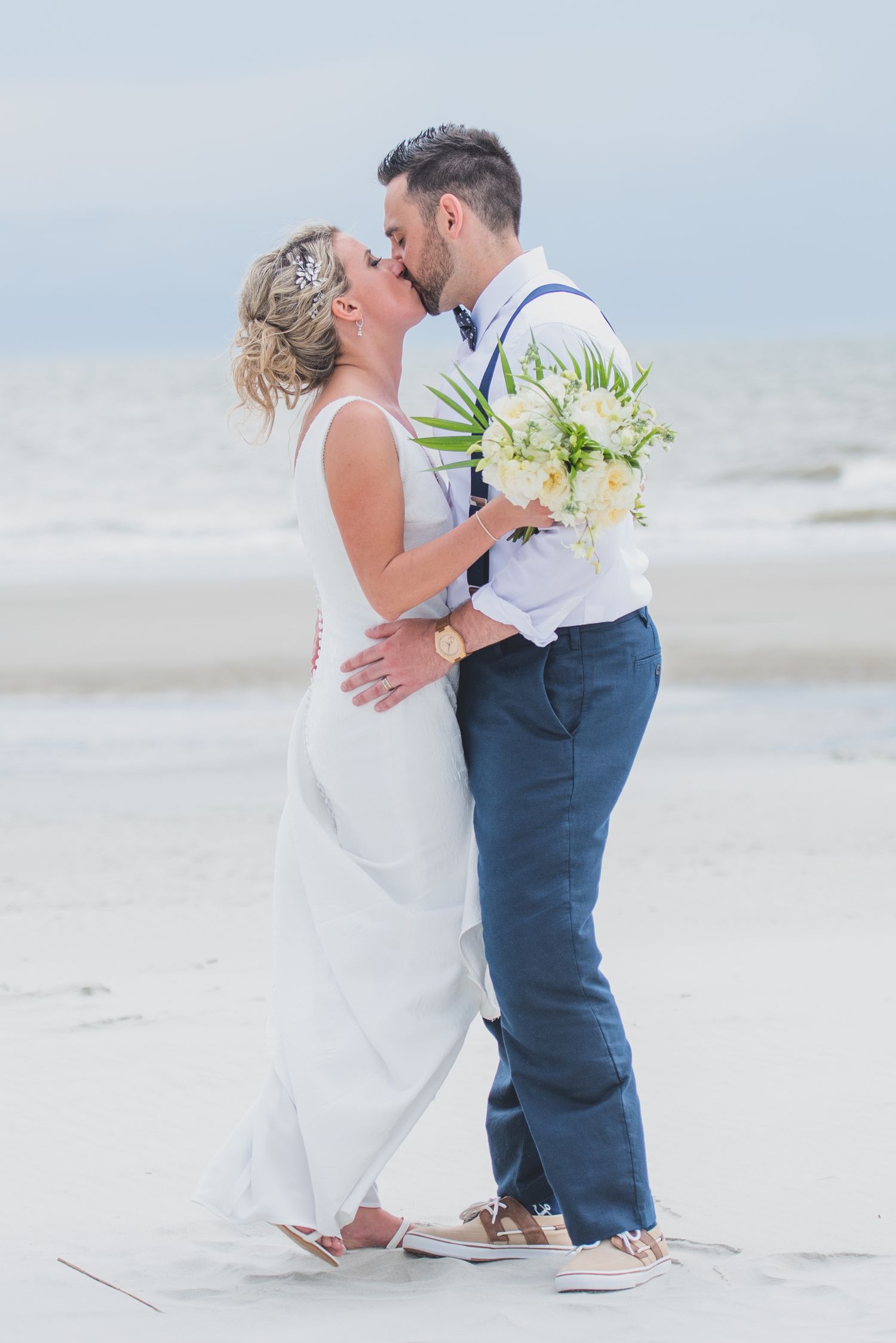 Hilton Head Newlyweds share romantic moments on sandy beach with ocean waves in background.