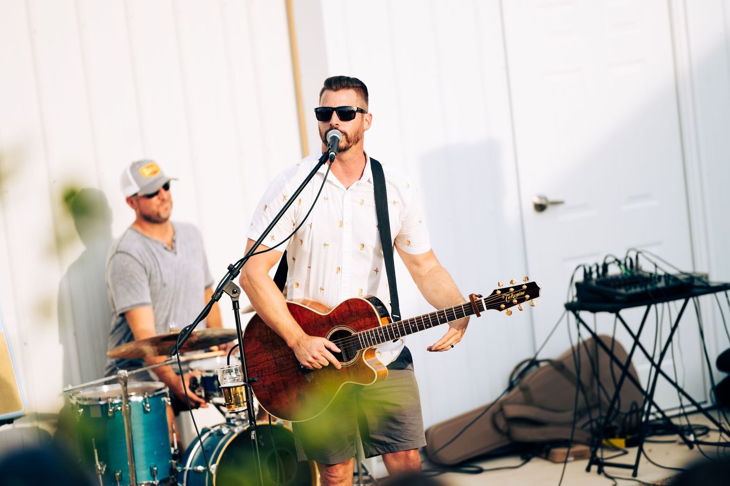 Musicians performing at an outdoor event with guitars and instruments on a sunny day.