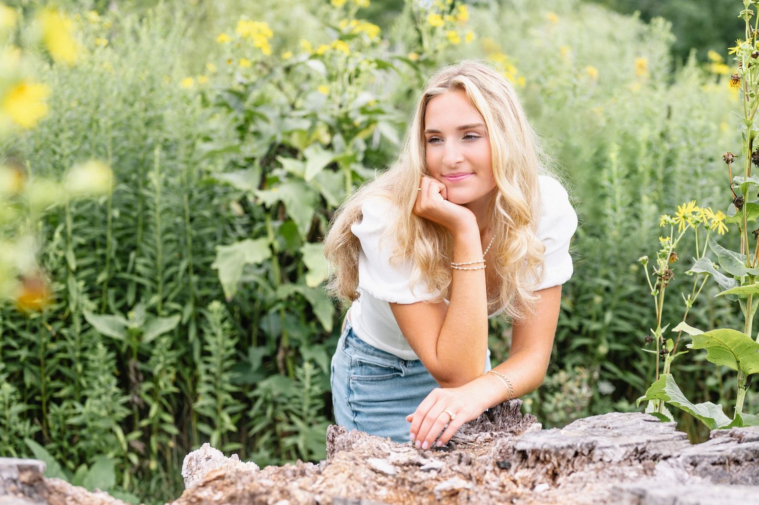 Outdoor portrait session in sunlit garden with yellow wildflowers.